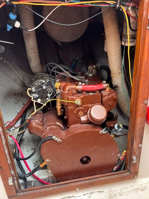 An engine compartment with an old engine, surrounded by wires and hoses.