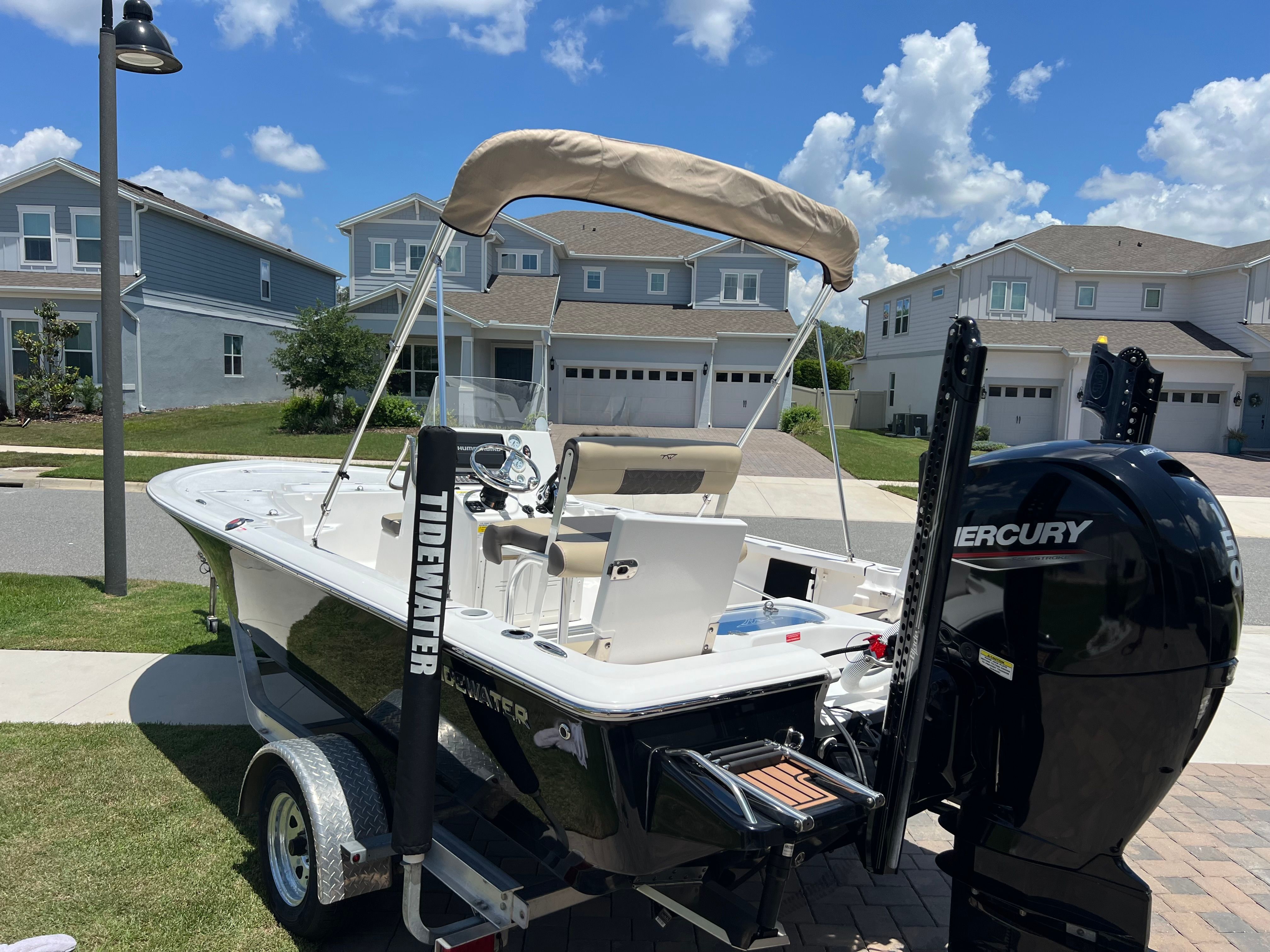A 2021 Tidewater 1910 Bay Max boat on a trailer in a residential area.