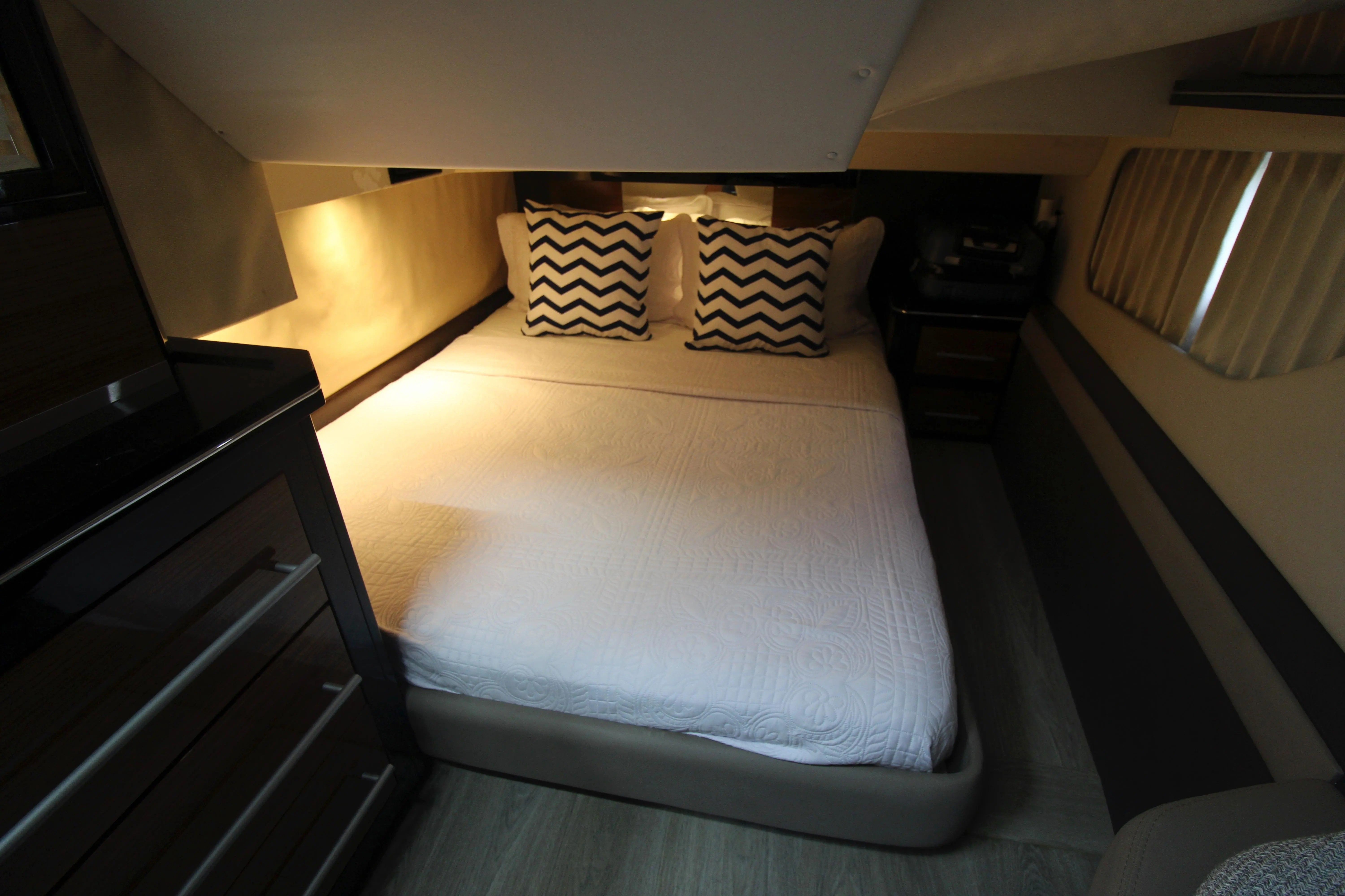 The image shows a cozy cabin with a double bed and decorative pillows.