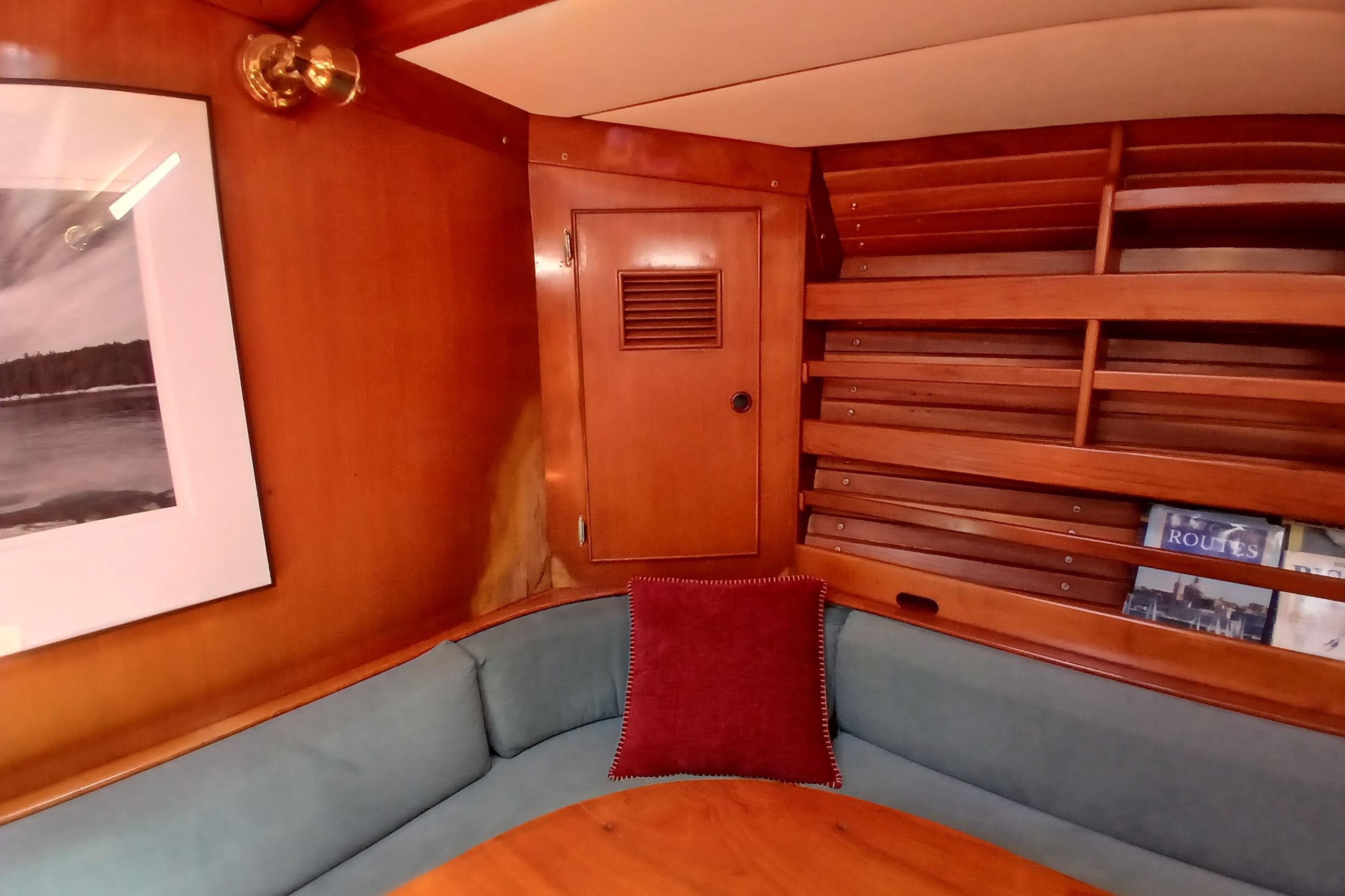 Cozy wooden yacht interior with cushioned seating, bookshelf, and framed artwork, SKYE 51, 1981.