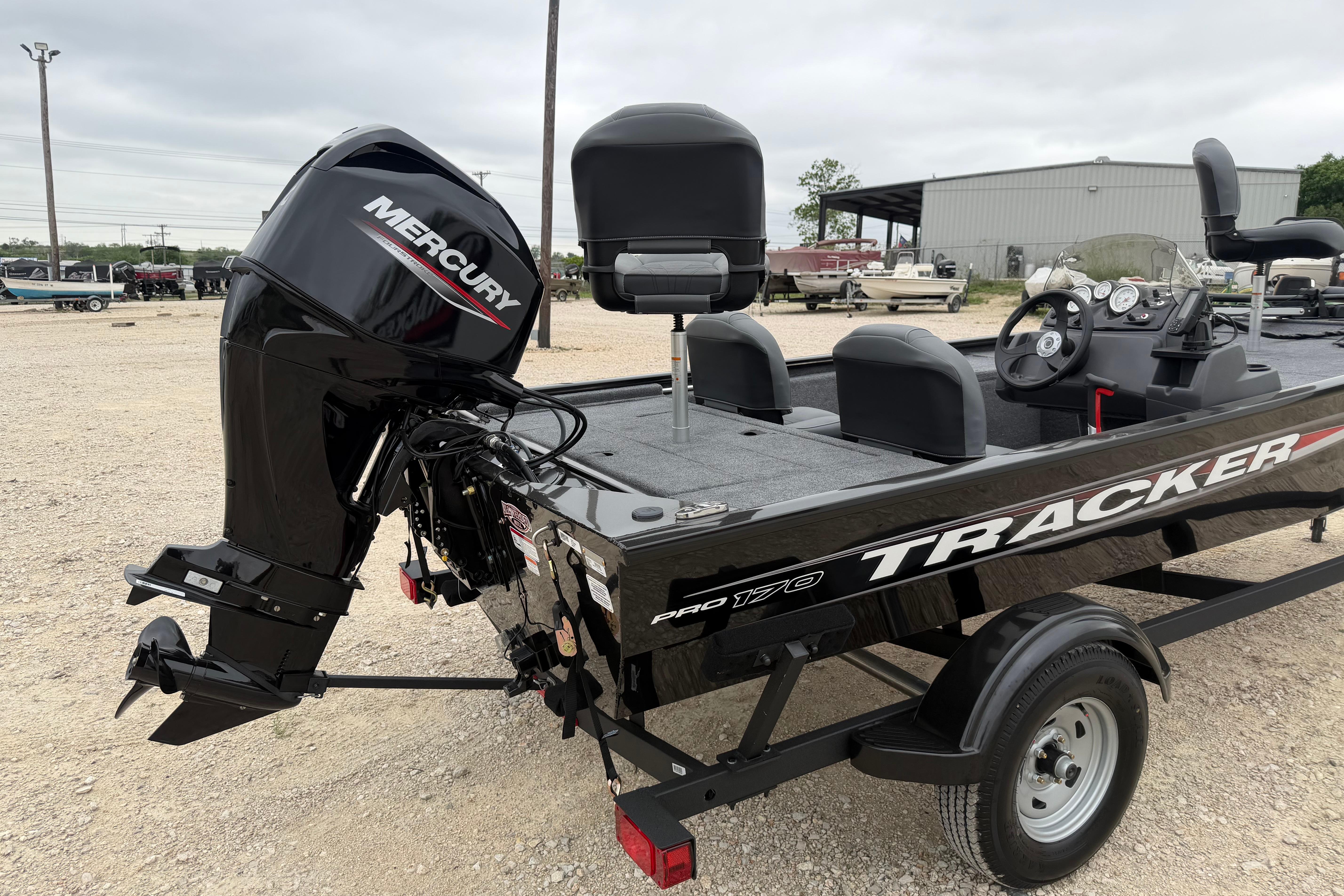 2026 Tracker Pro 170 boat with Mercury outboard motor in a gravel lot.