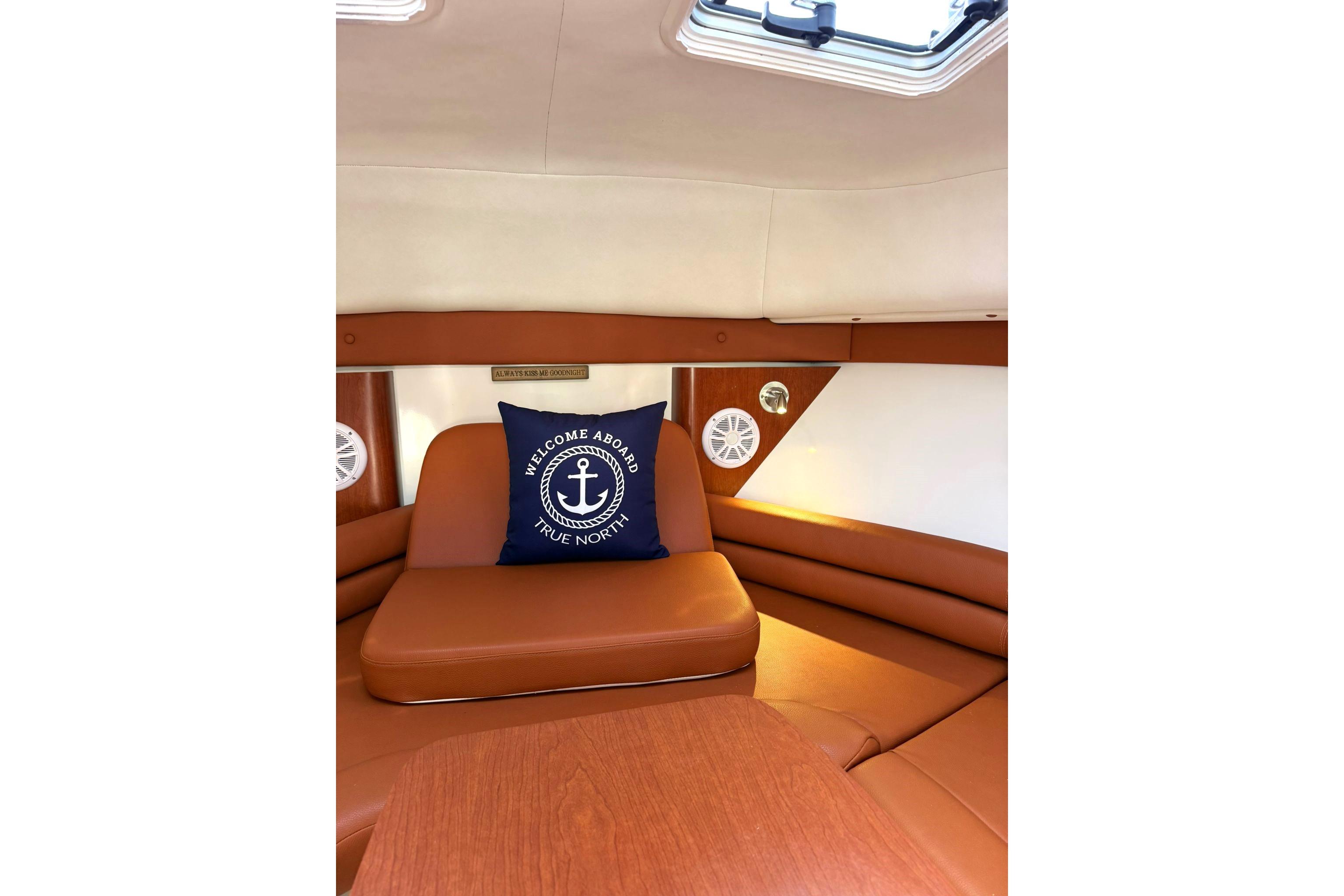 Interior of 2006 Pro-Line 32 Express boat with cozy seating and nautical-themed pillow.