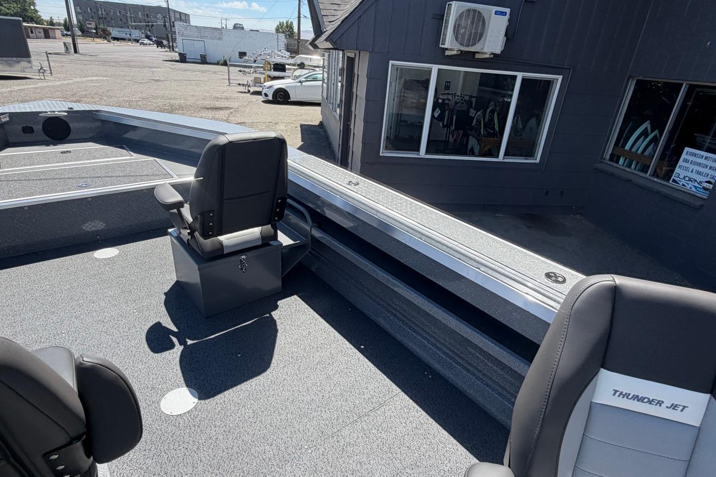 2026 Thunder Jet 209 Rush OT boat interior with seating and storage, parked outside a building.