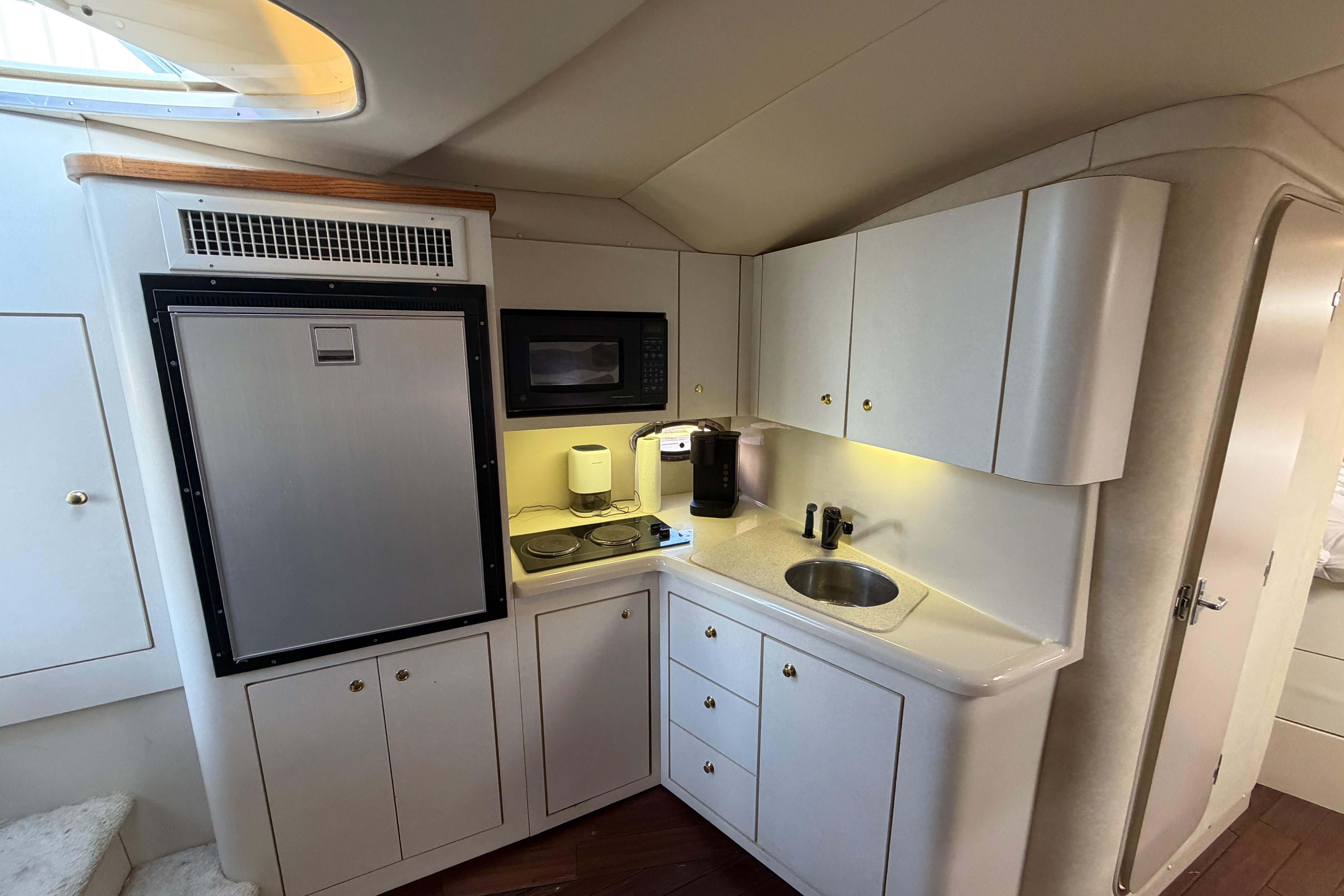 1997 Cruisers 3575 yacht kitchen with fridge, microwave, sink, and cabinets.