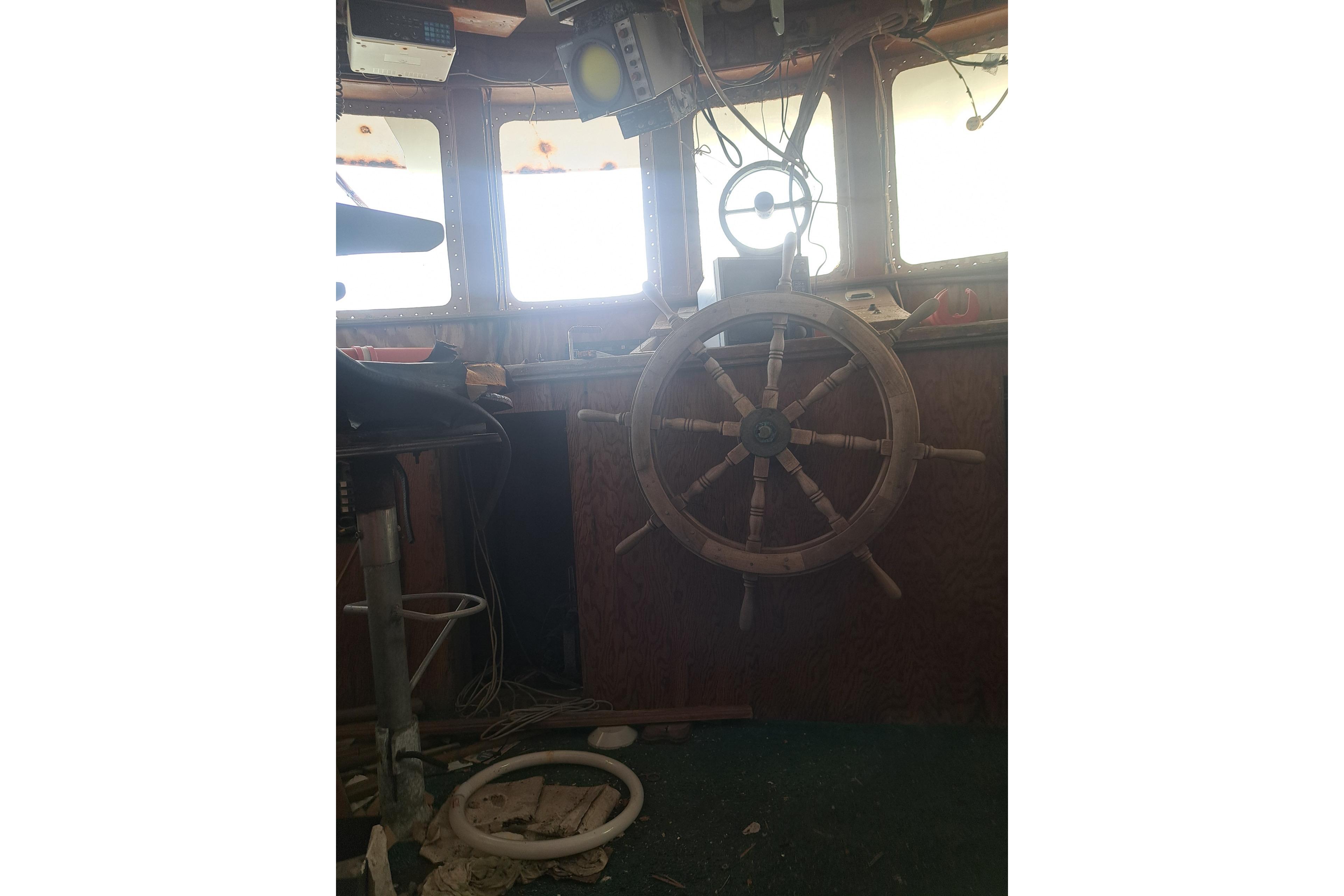 Interior of 1979 Custom Steel Trawler Dragger with wooden ship wheel and navigation equipment.