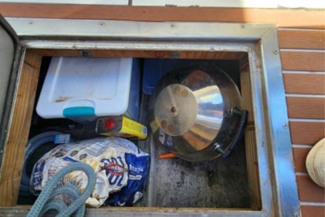 Storage compartment on a 1985 Wasque Down East Cruiser with various boating supplies.