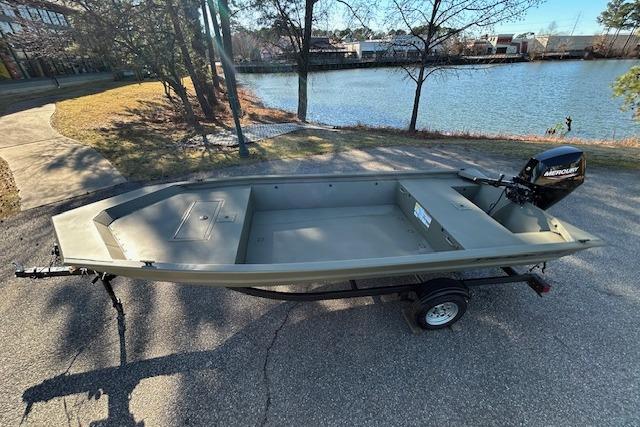 2026 Tracker Grizzly 1648 Utility boat on trailer by a lakeside.