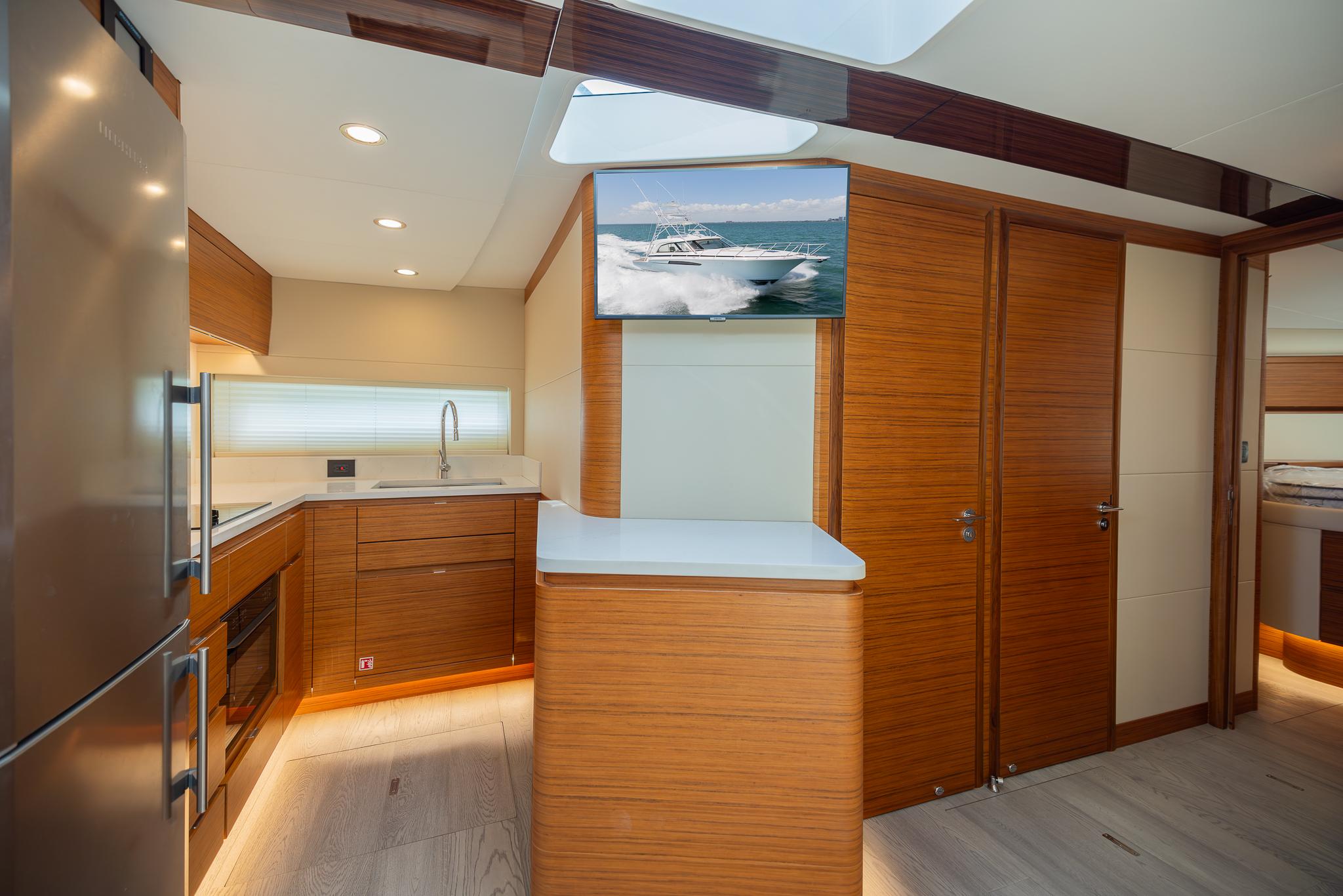 Modern kitchen interior of 2022 Bertram 50 yacht with wood finishes and stainless steel appliances.