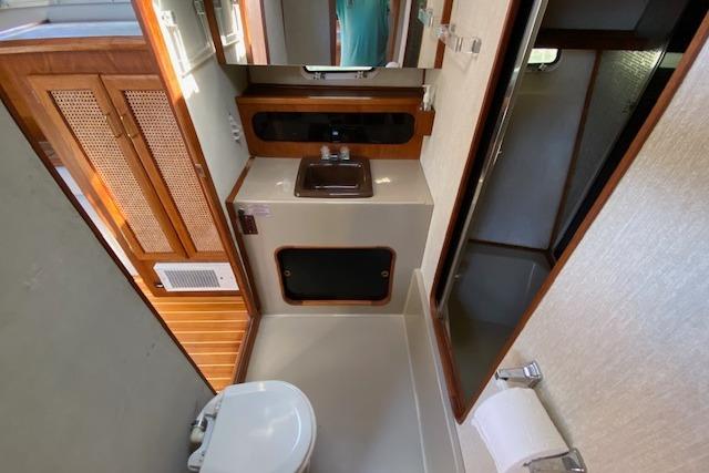 1985 Bayliner 3870 Motoryacht bathroom with sink, toilet, and wooden cabinetry.
