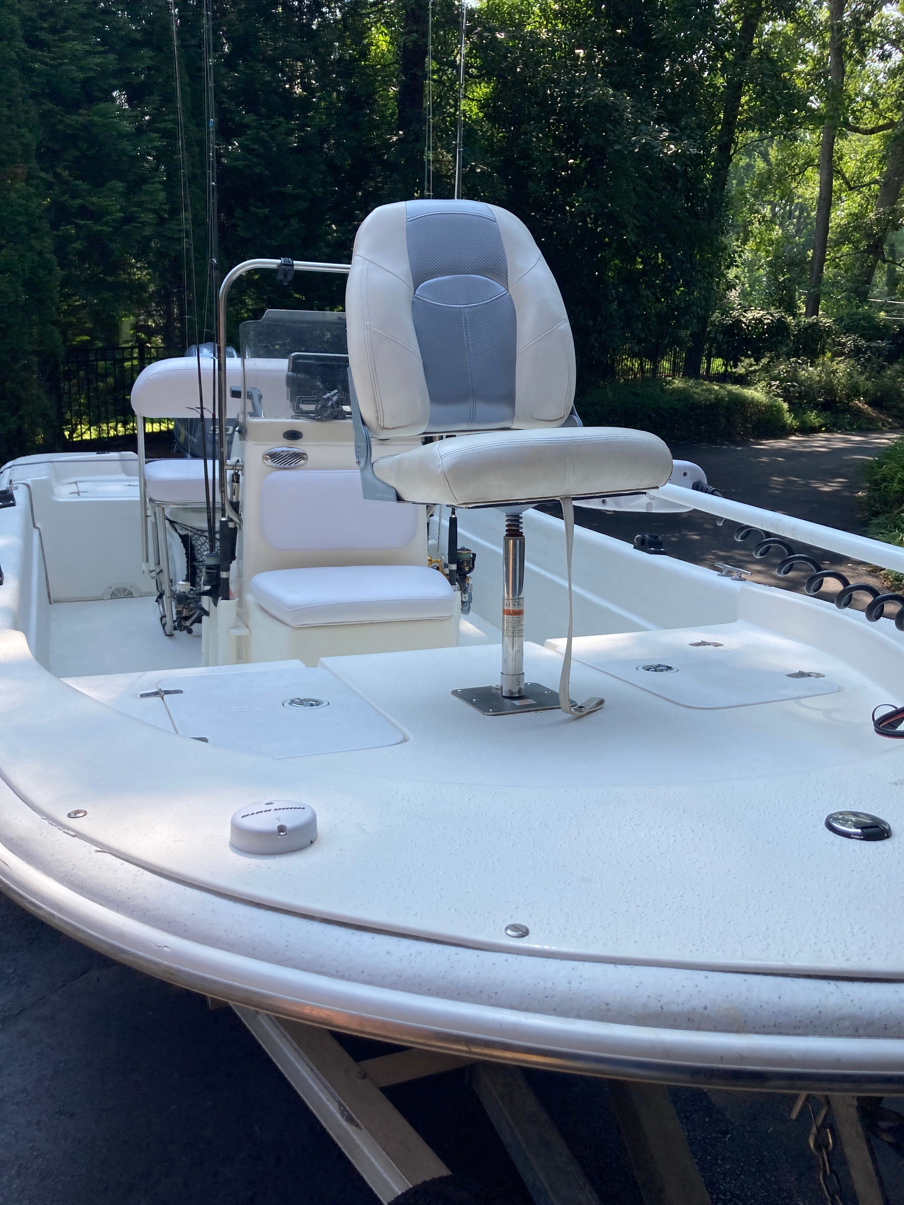 A 2012 Carolina Skiff JVX16CC with a white seat and console, surrounded by trees.