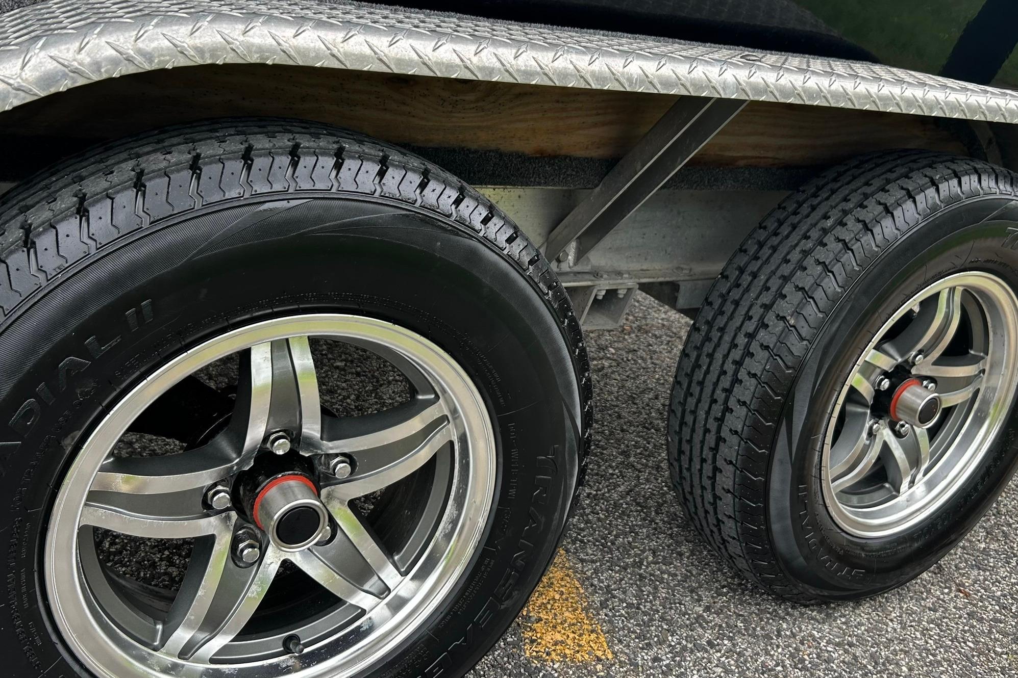 Trailer wheels of a 2015 NauticStar 231 Coastal boat on pavement.