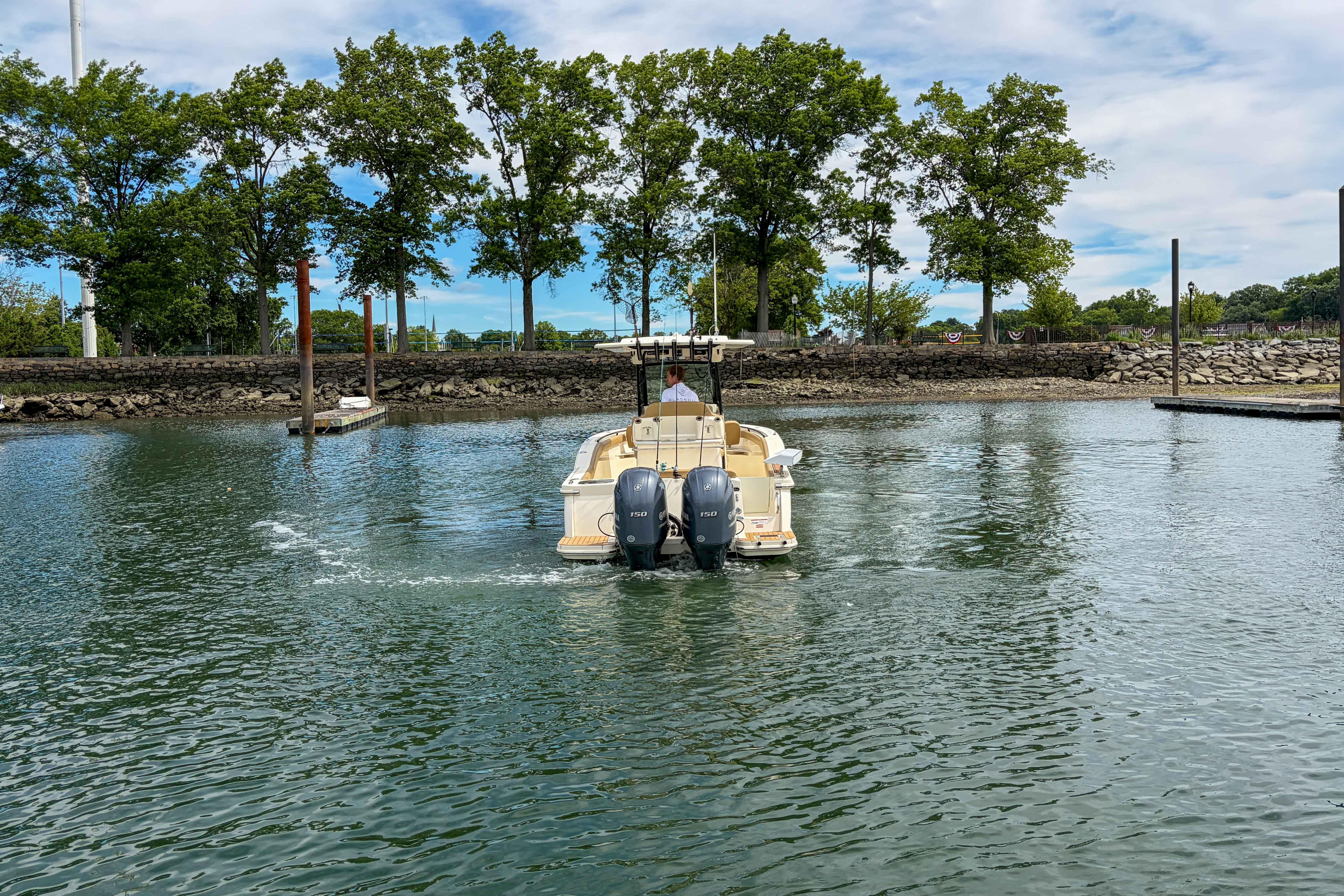 2020 Scout 255 LXF boat navigating calm waters near a tree-lined shore.
