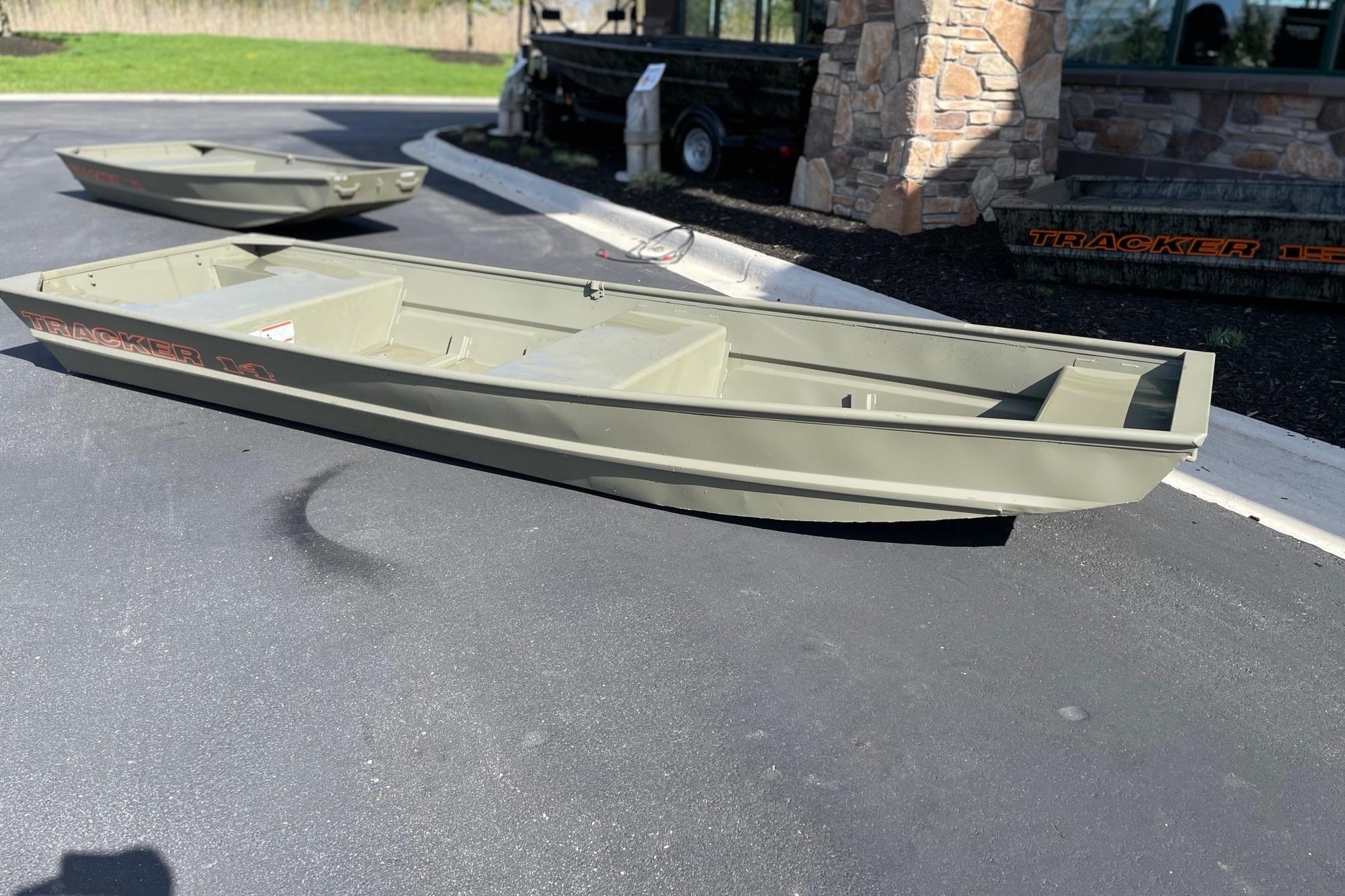 2026 Tracker Grizzly 14 Jon boat displayed on pavement near a stone building.
