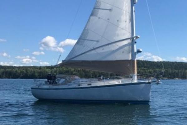 1989 Nonsuch 30 Ultra sailboat on calm water under a clear blue sky.