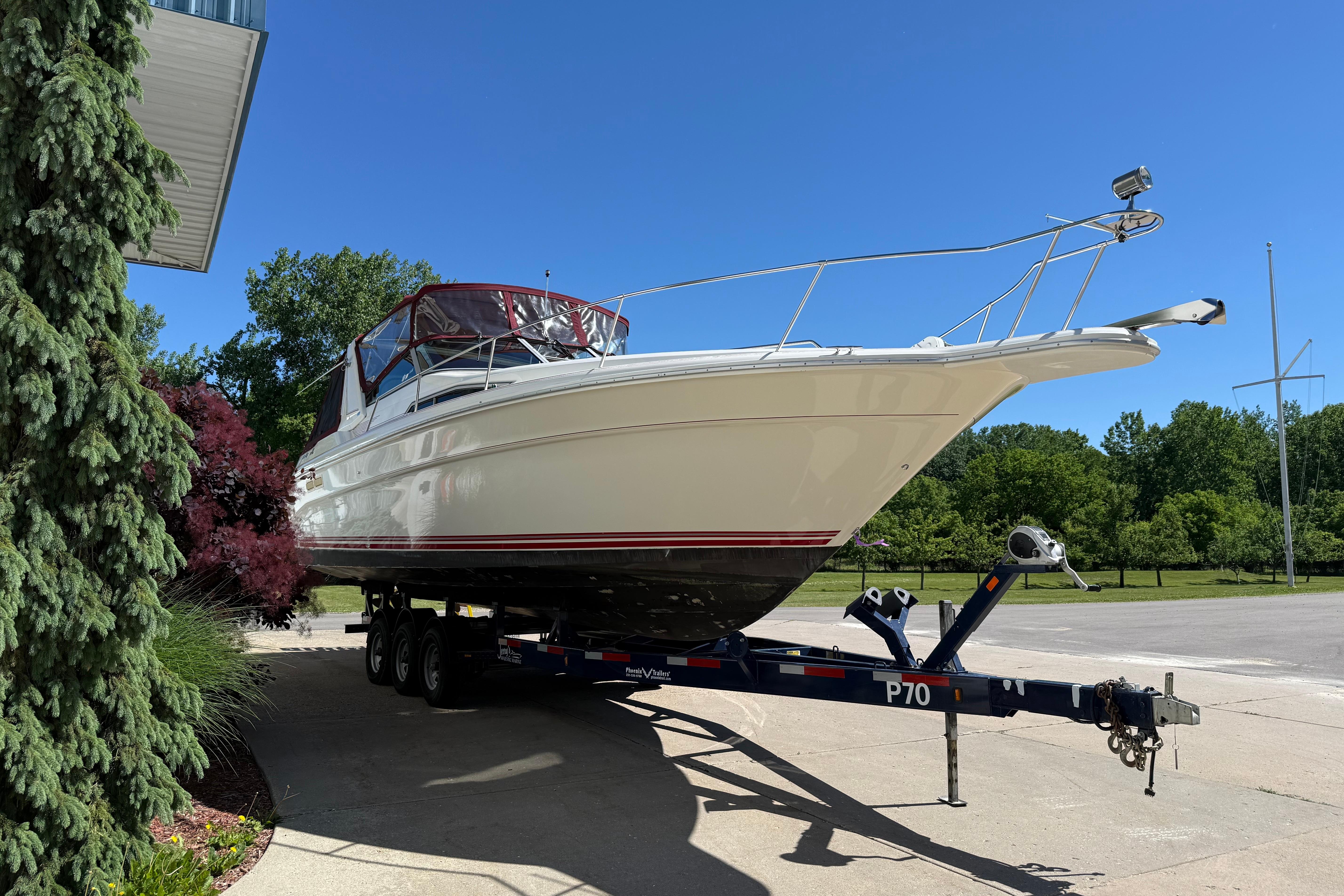 1990 Sea Ray 310 Express Cruiser on trailer, parked outdoors under clear blue sky.