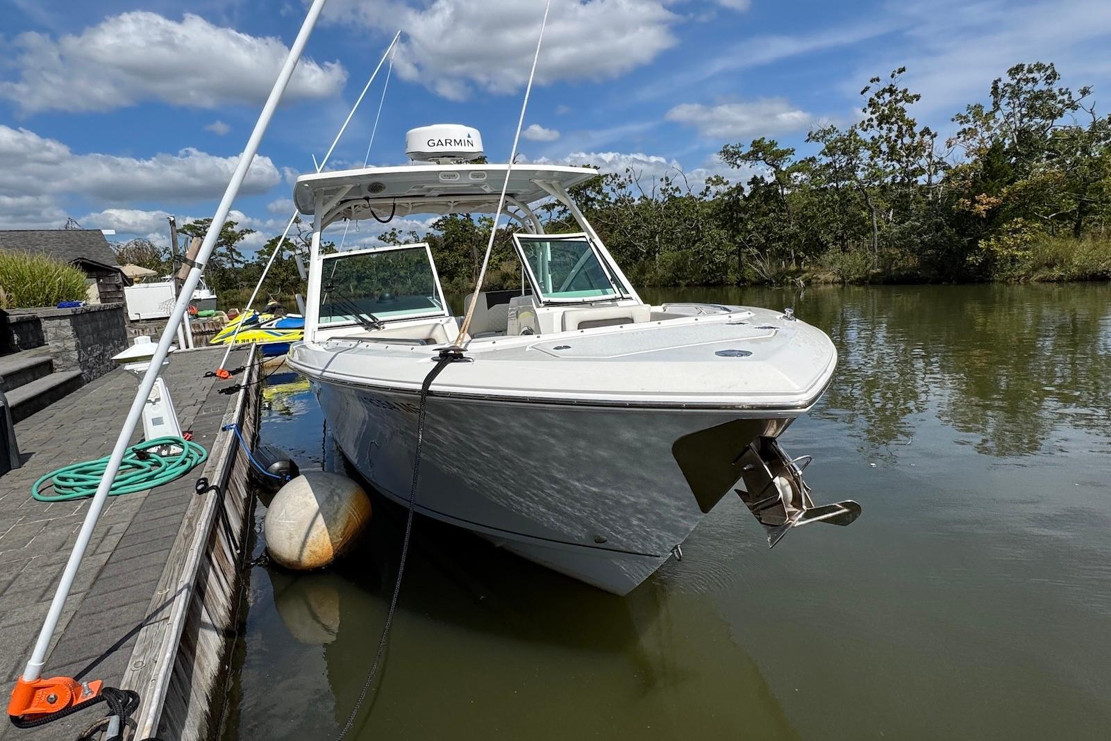 2022 Sailfish 276 DC boat docked on a calm river under a blue sky.