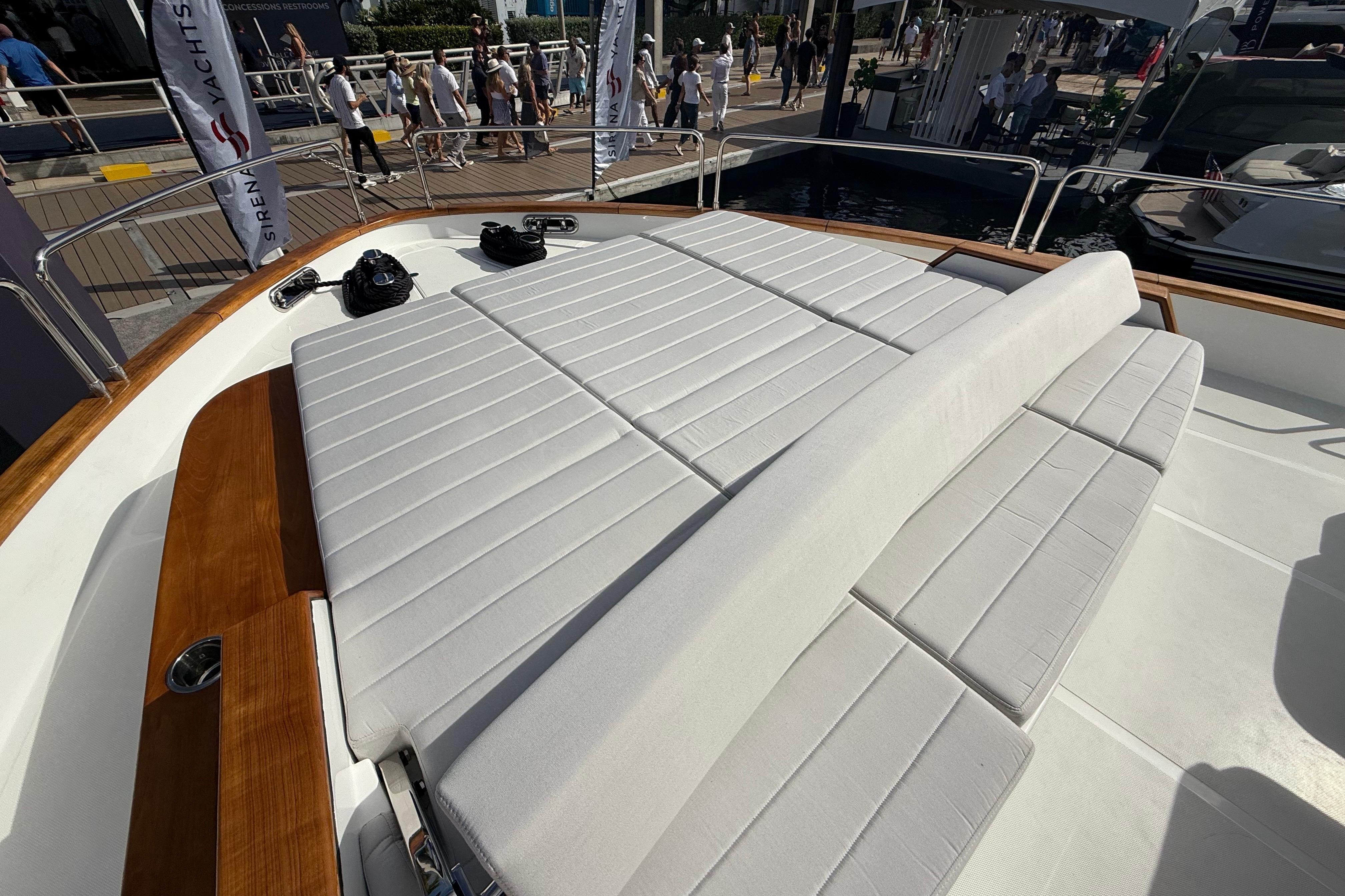 Luxurious sunbathing area on the 2026 Sirena 68 yacht, featuring plush white cushions.