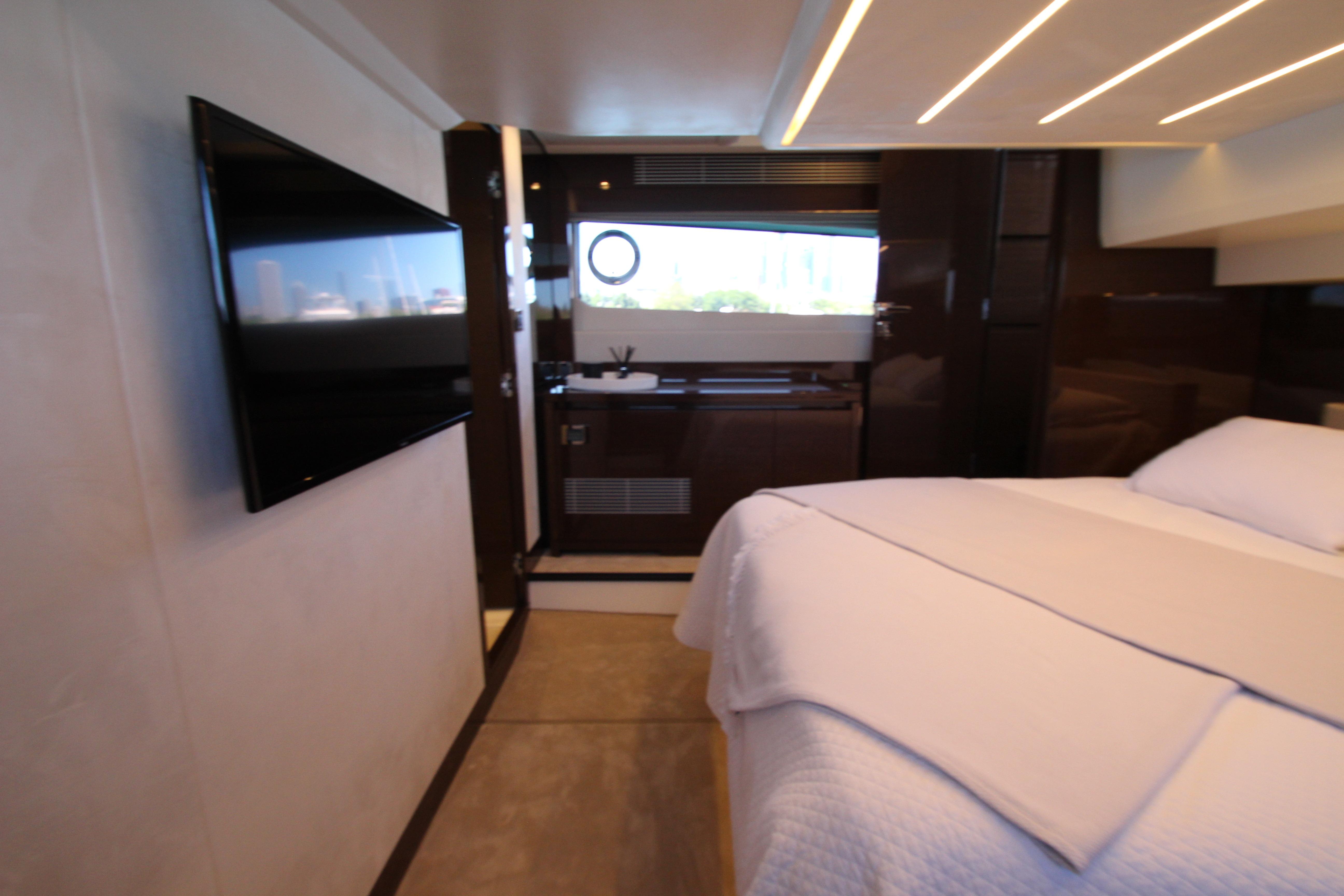 Luxurious interior of 2022 Prestige 520 yacht with modern bedroom and flat-screen TV.