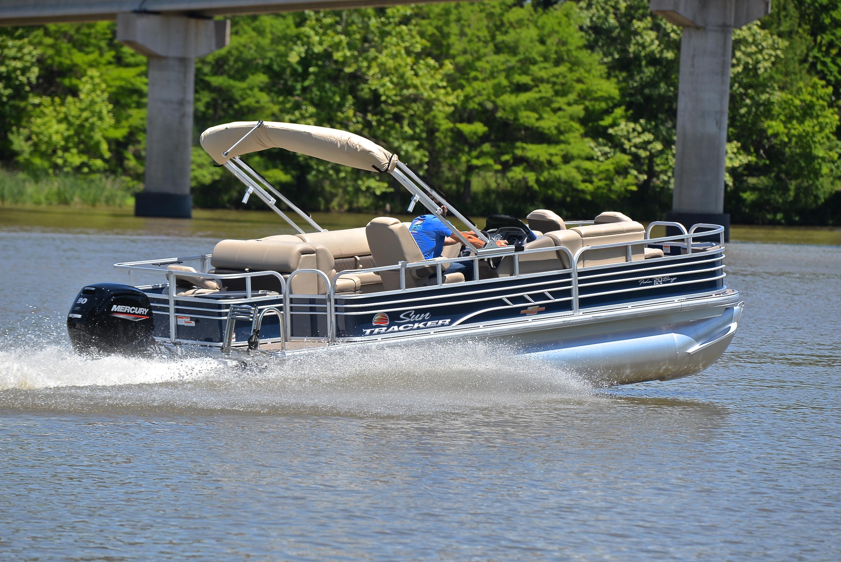 2023 Sun Tracker Fishin Barge 20 DLX pontoon boat cruising on a lake.