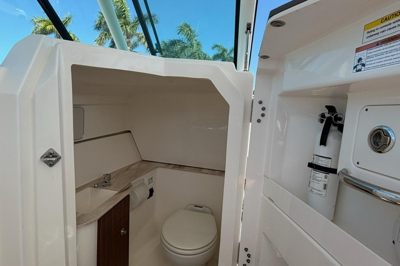 2021 Pursuit DC 266 Dual Console boat interior with toilet and fire extinguisher.
