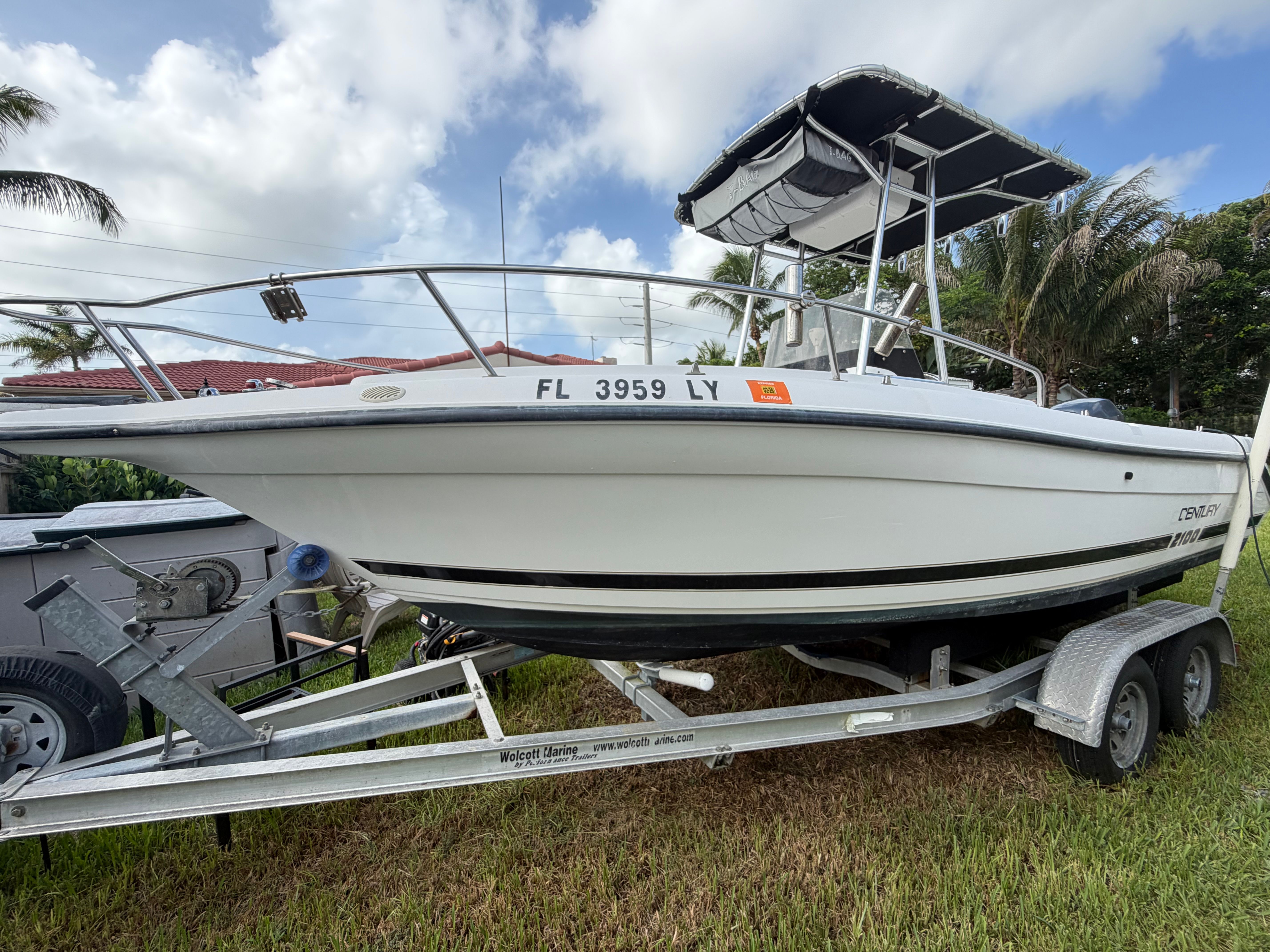 A 2001 Century 2100 Center Console boat on a trailer, surrounded by palm trees.