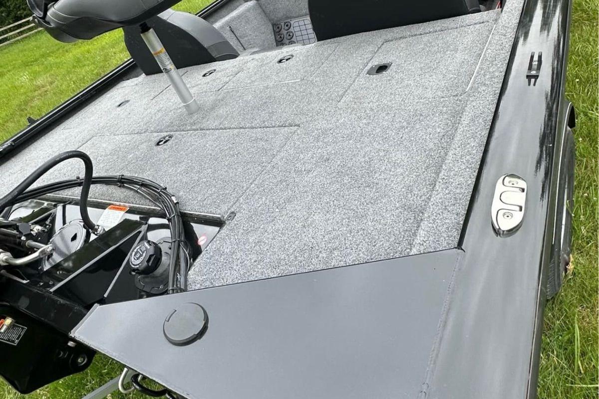 2022 Bass Tracker 195TXW boat deck with seating and control panel, parked on grass.