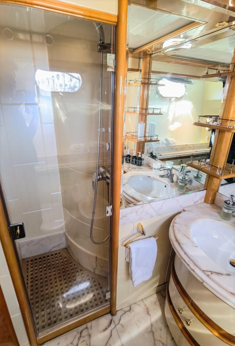 Luxurious bathroom in 1997 Astondoa 95 GLX yacht with marble sink and glass shower.
