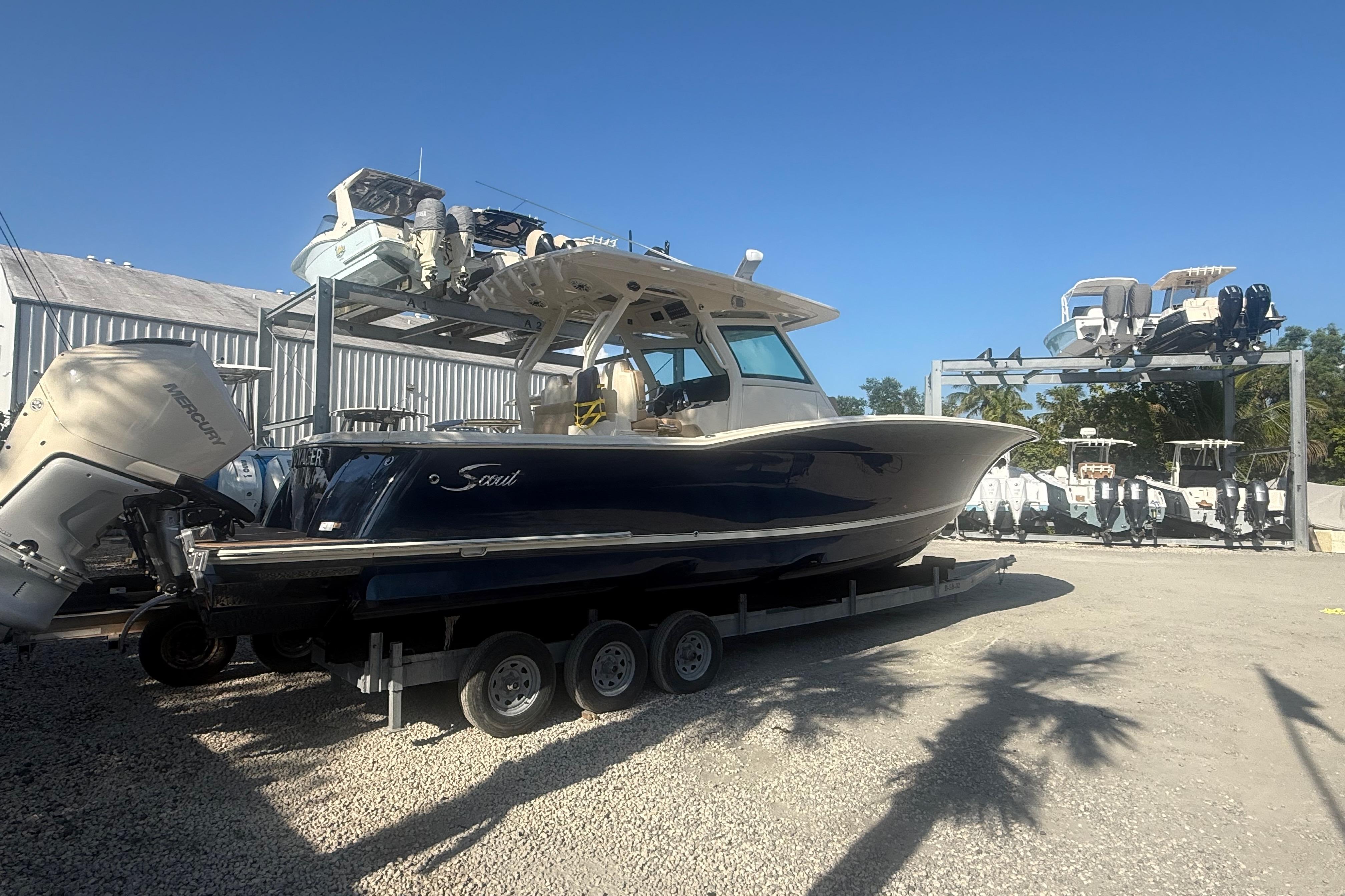 2022 Scout 355 LXF boat on trailer, parked outdoors under clear blue sky.