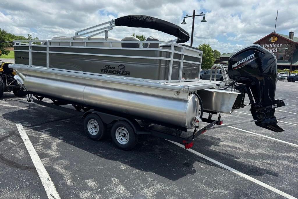 2026 Sun Tracker Fishin' Barge 20 DLX pontoon boat on trailer in parking lot.