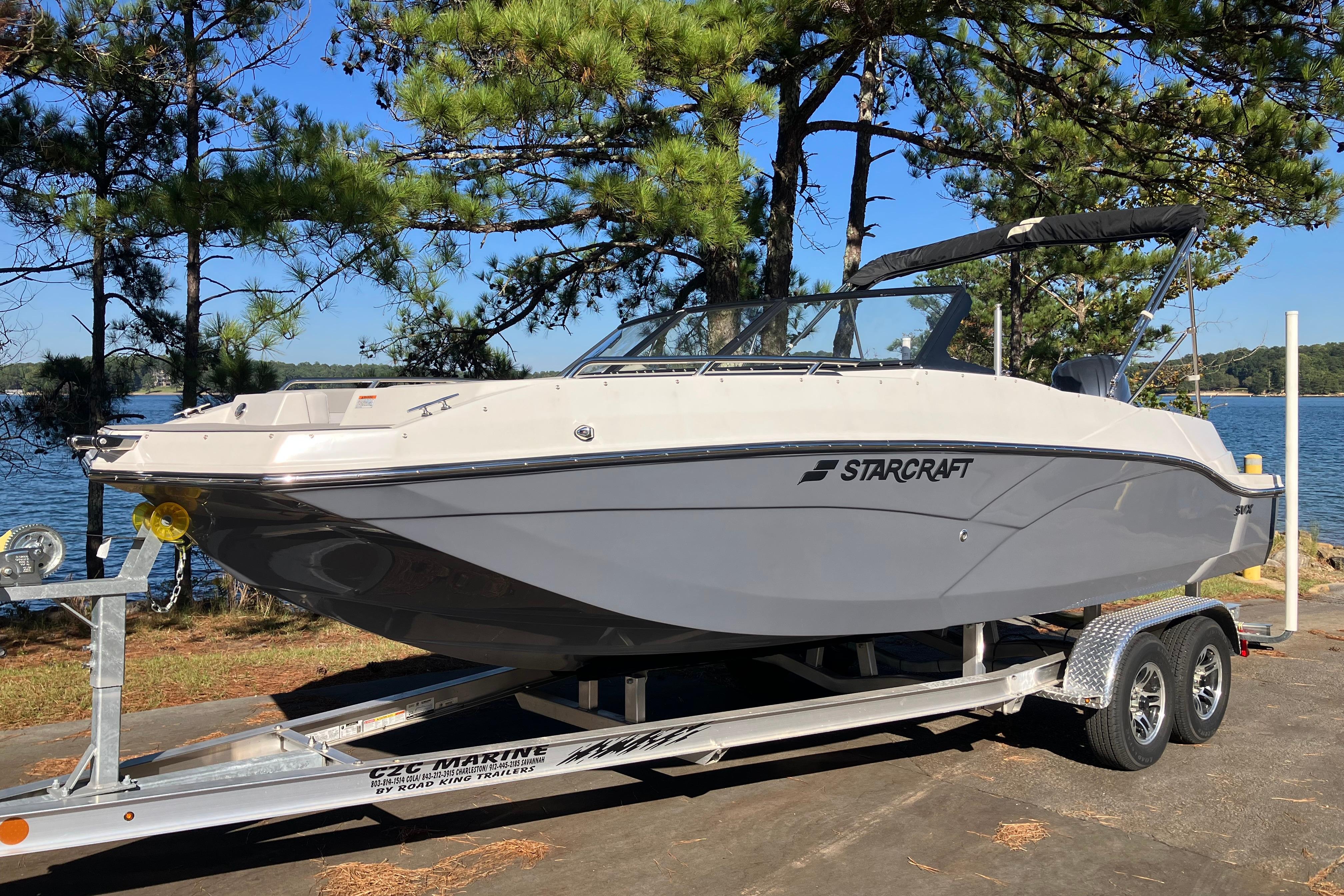 2025 Starcraft SVX 210 OB boat on trailer by a scenic lake.