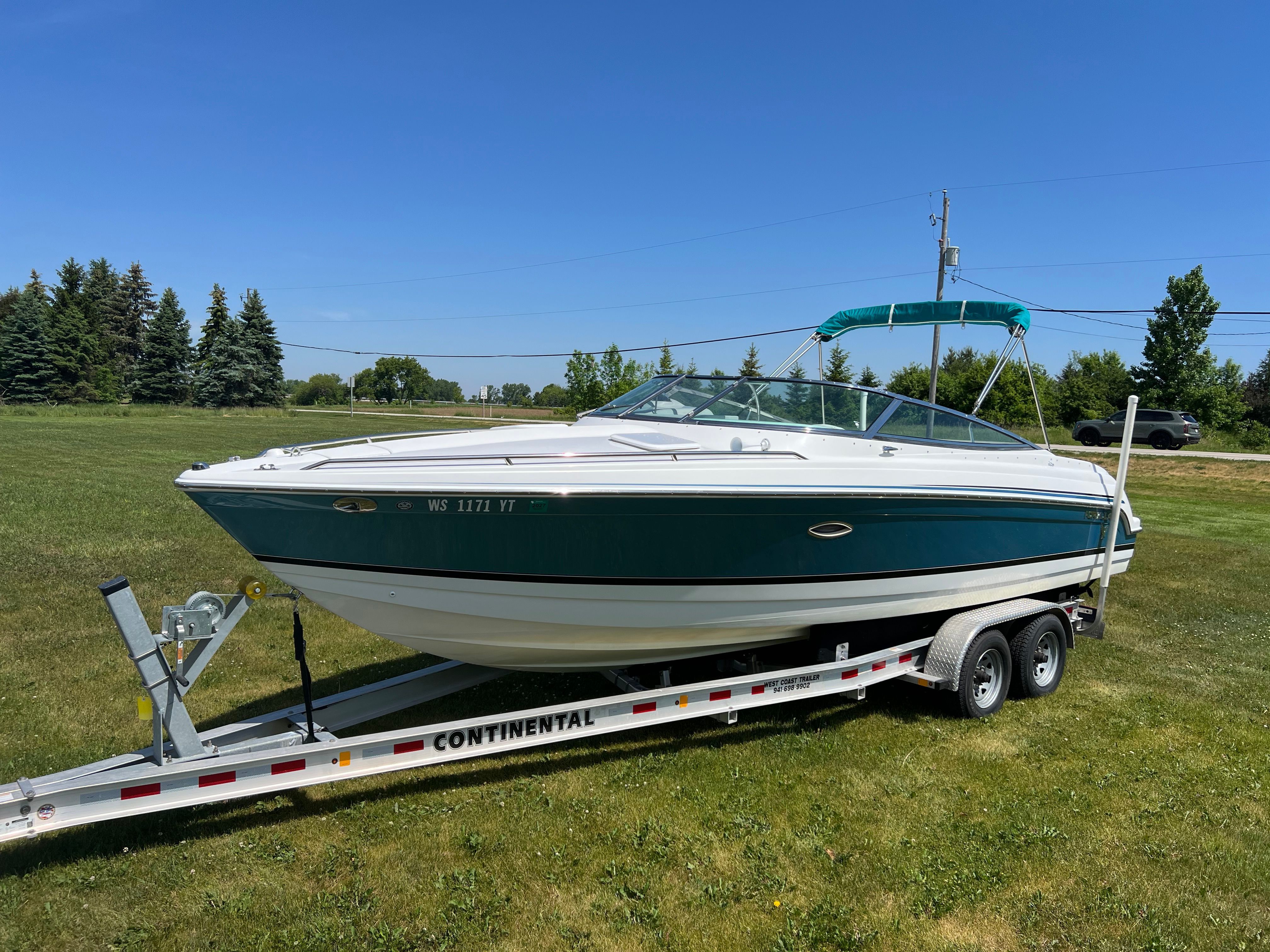 A 2005 Formula 260 Sun Sport boat on a trailer, parked on a grassy field.