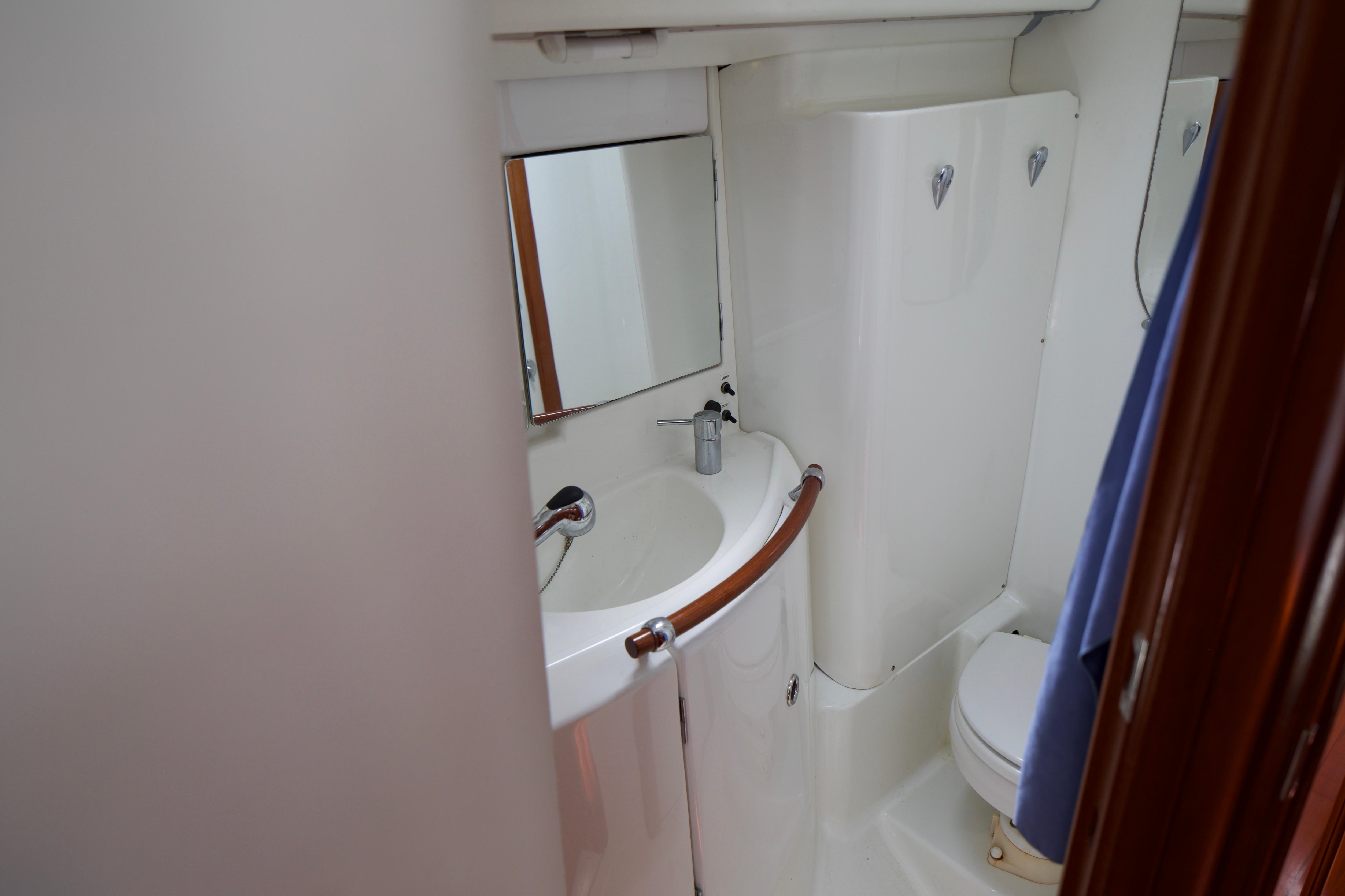 Bathroom interior of 2005 Beneteau 423 yacht, featuring sink, mirror, and toilet.