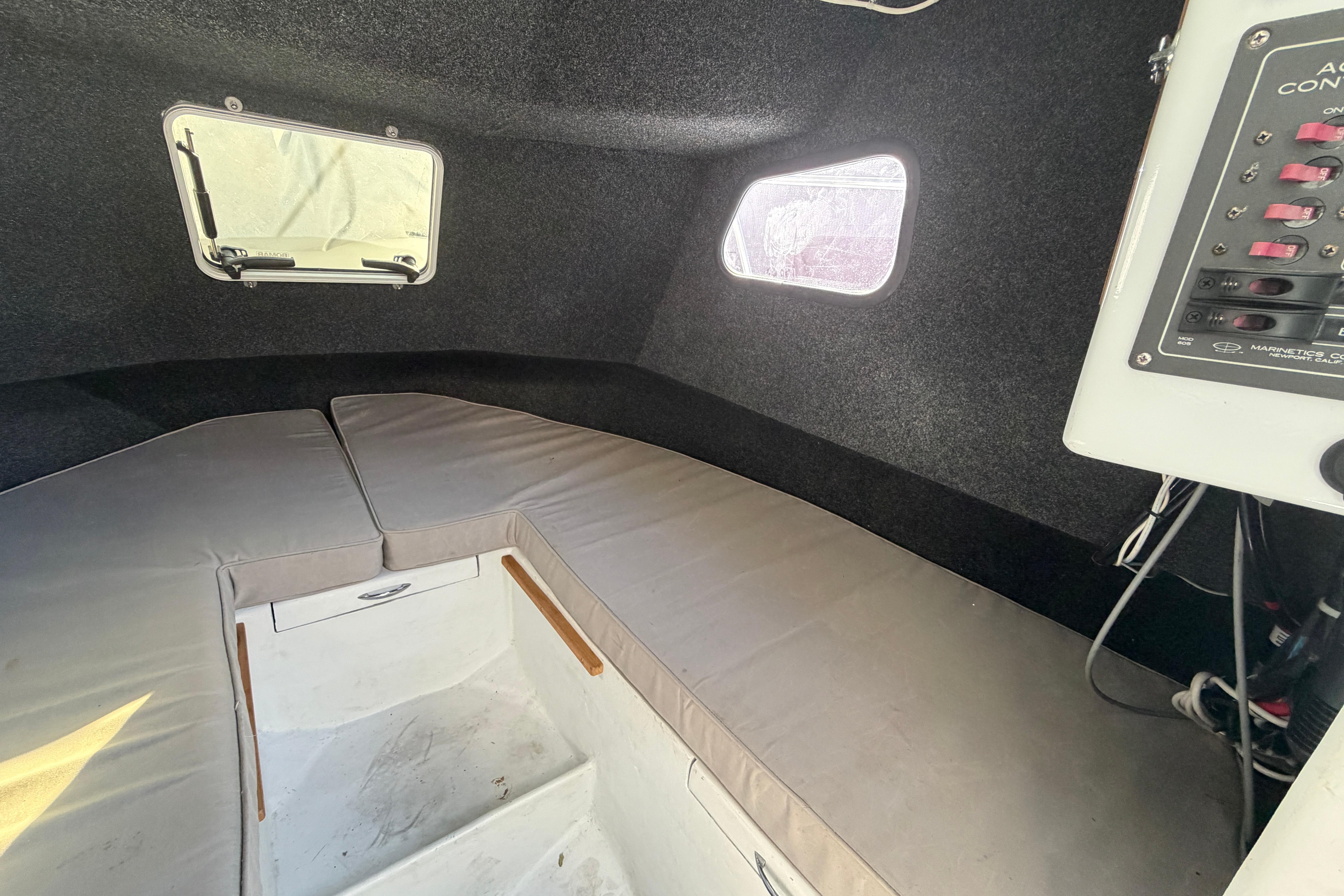 Interior cabin of a 1986 Radon 21 Sport boat with cushioned seating and control panel.