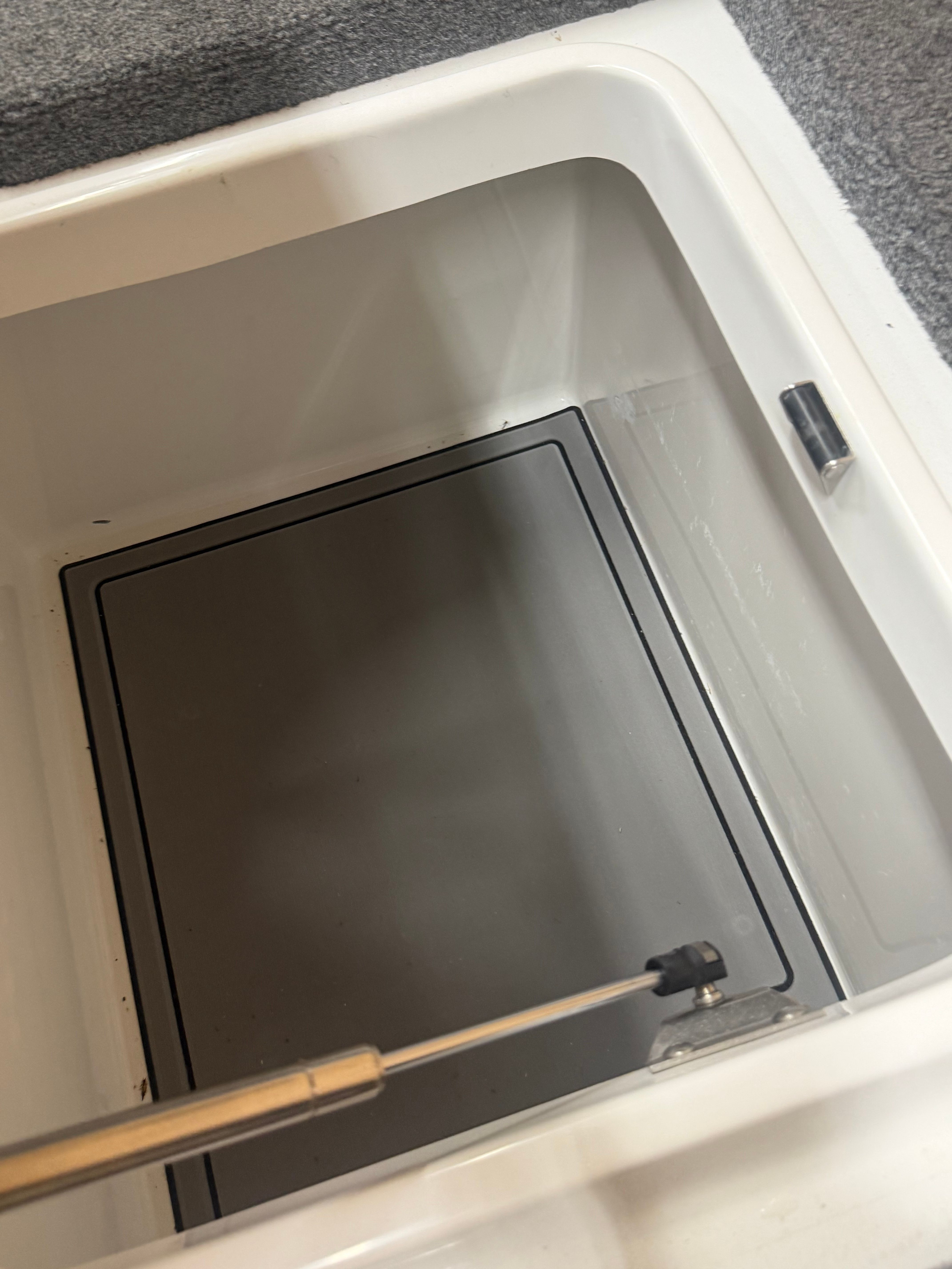 Interior view of a storage compartment with a hydraulic support arm.