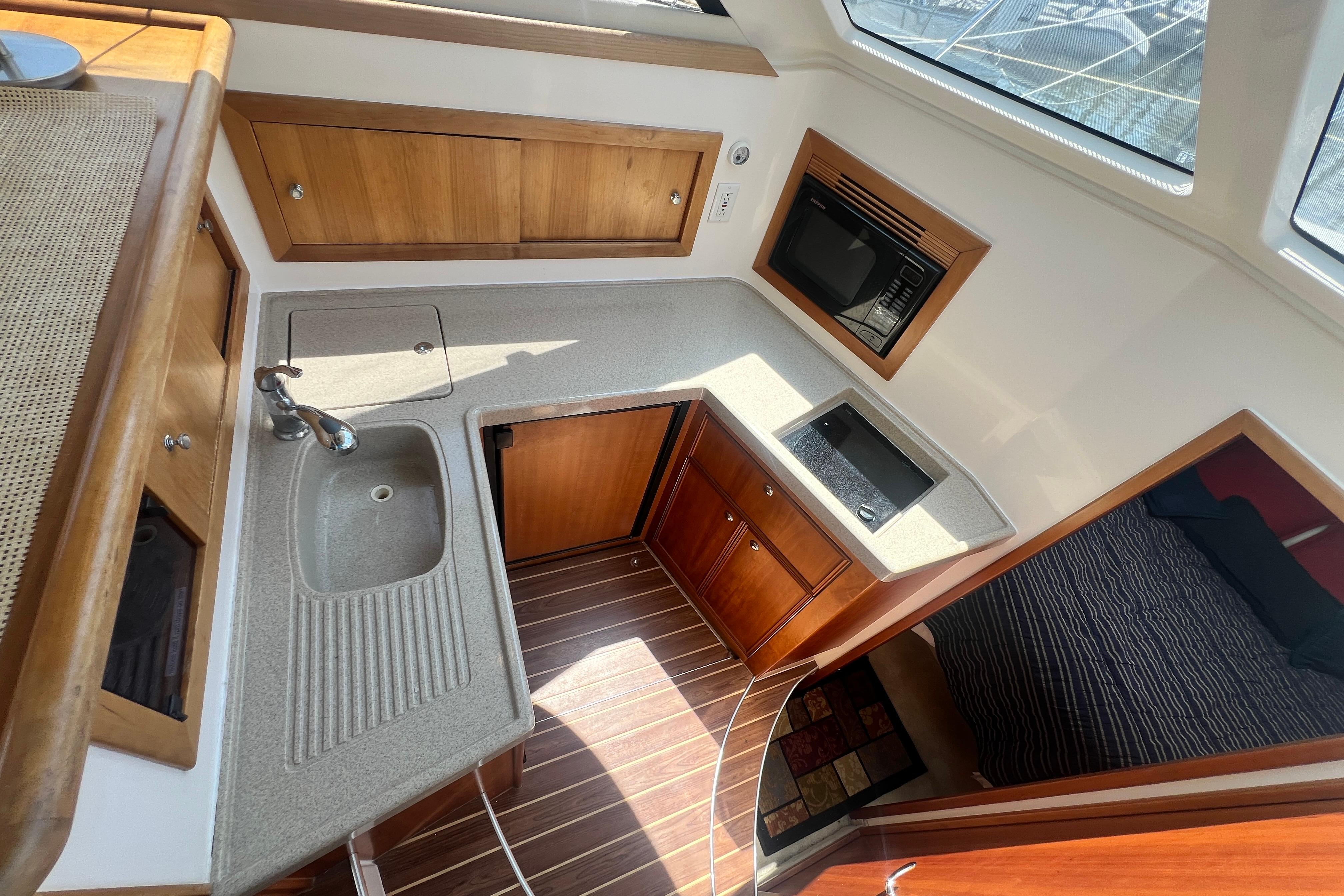 2007 Riviera 33 Flybridge yacht kitchen with sink, stove, and wooden cabinetry.