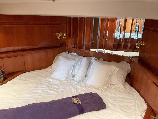 Luxurious bedroom interior of 2000 Novatec Islander 55 yacht with wooden paneling and plush bedding.