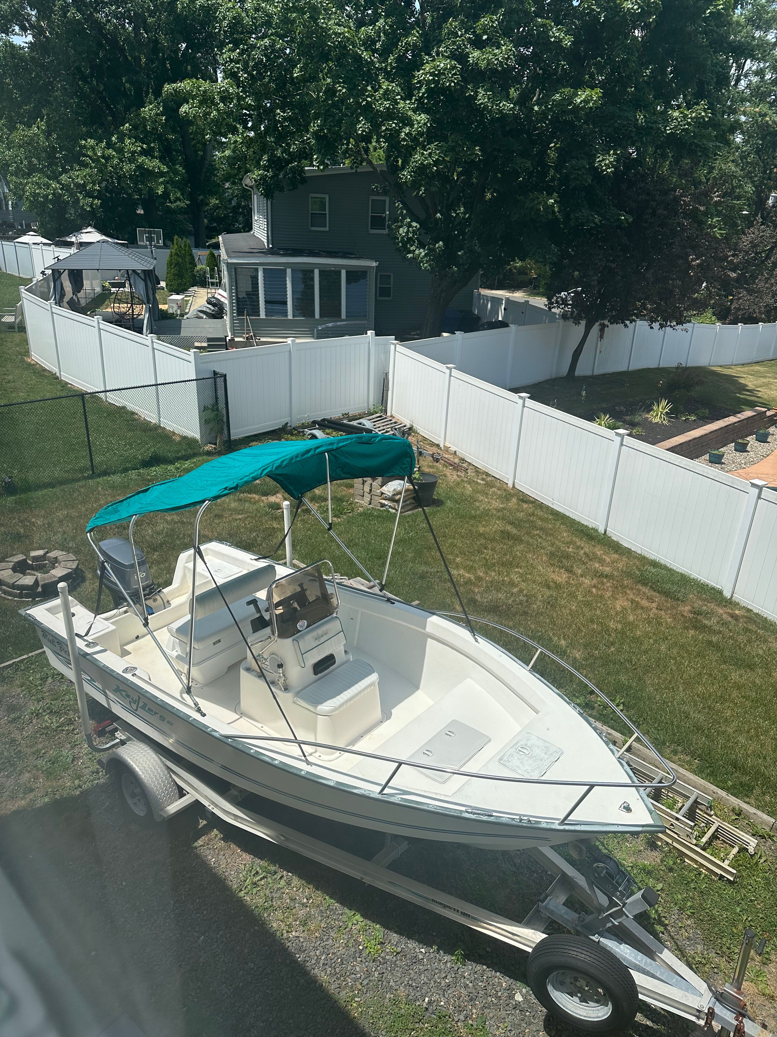 A 2003 Key Largo 180 Center Console boat on a trailer in a backyard.