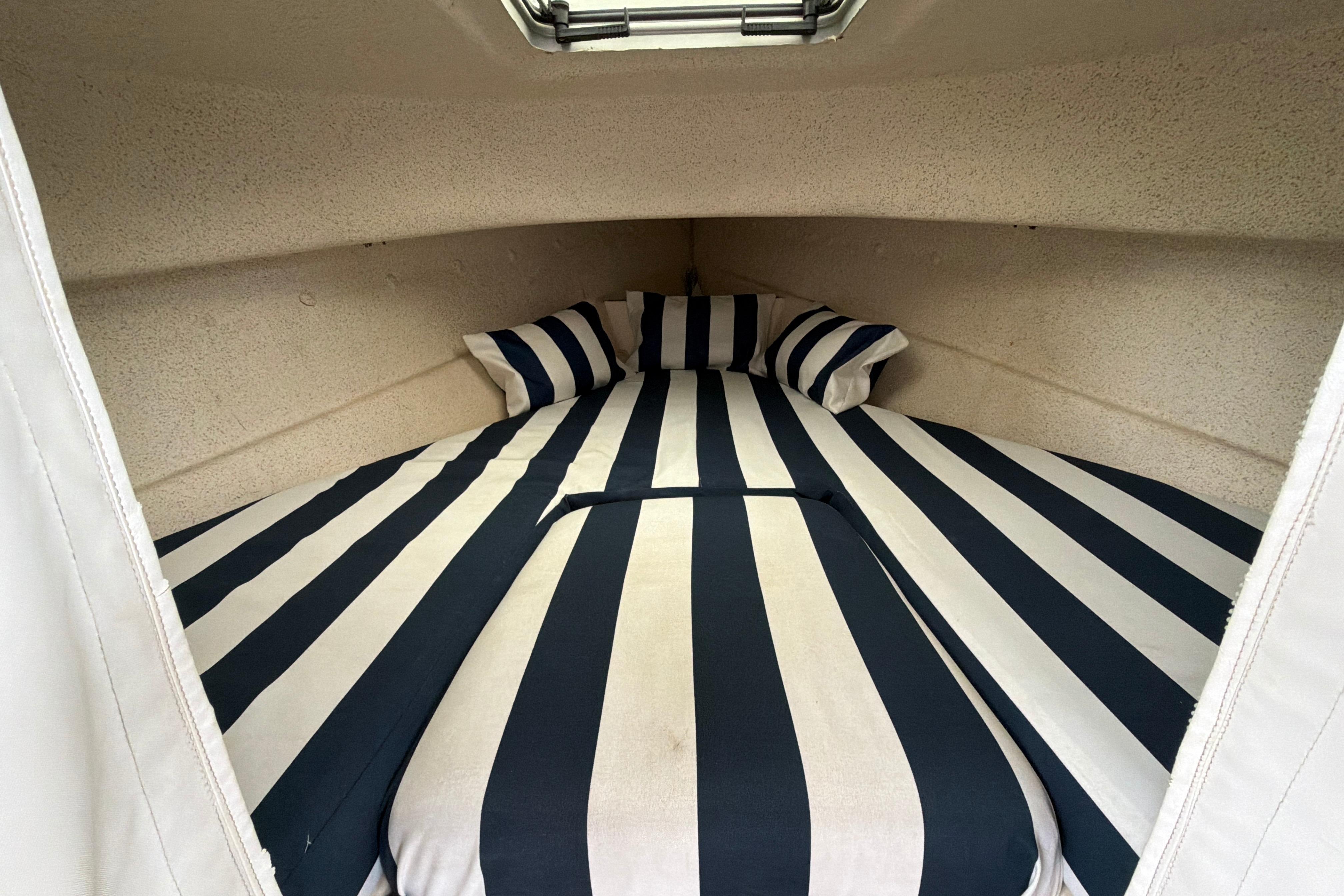 Cozy cabin interior of 1989 C-Dory 22' Angler with striped bedding.