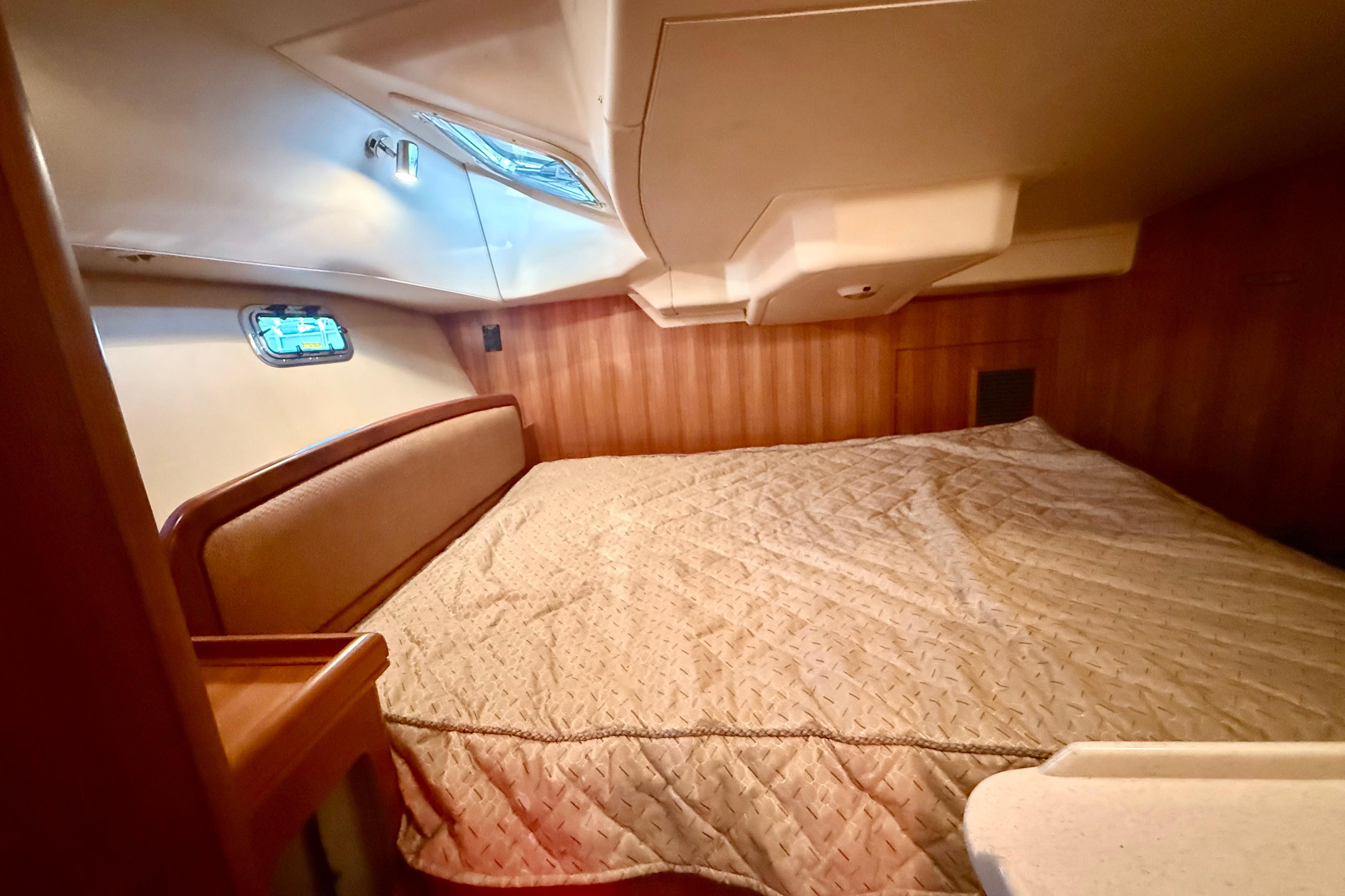 Cozy cabin interior of 2007 Hunter 41 Deck Salon yacht with wood paneling and bedding.