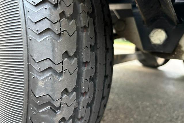 Close-up of a 2017 Searay SPX210 trailer tire on a wet surface.