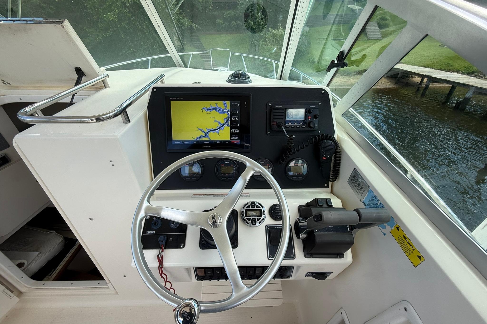 Helm of 2003 Pursuit 2870 Walkaround boat with navigation equipment and steering wheel.