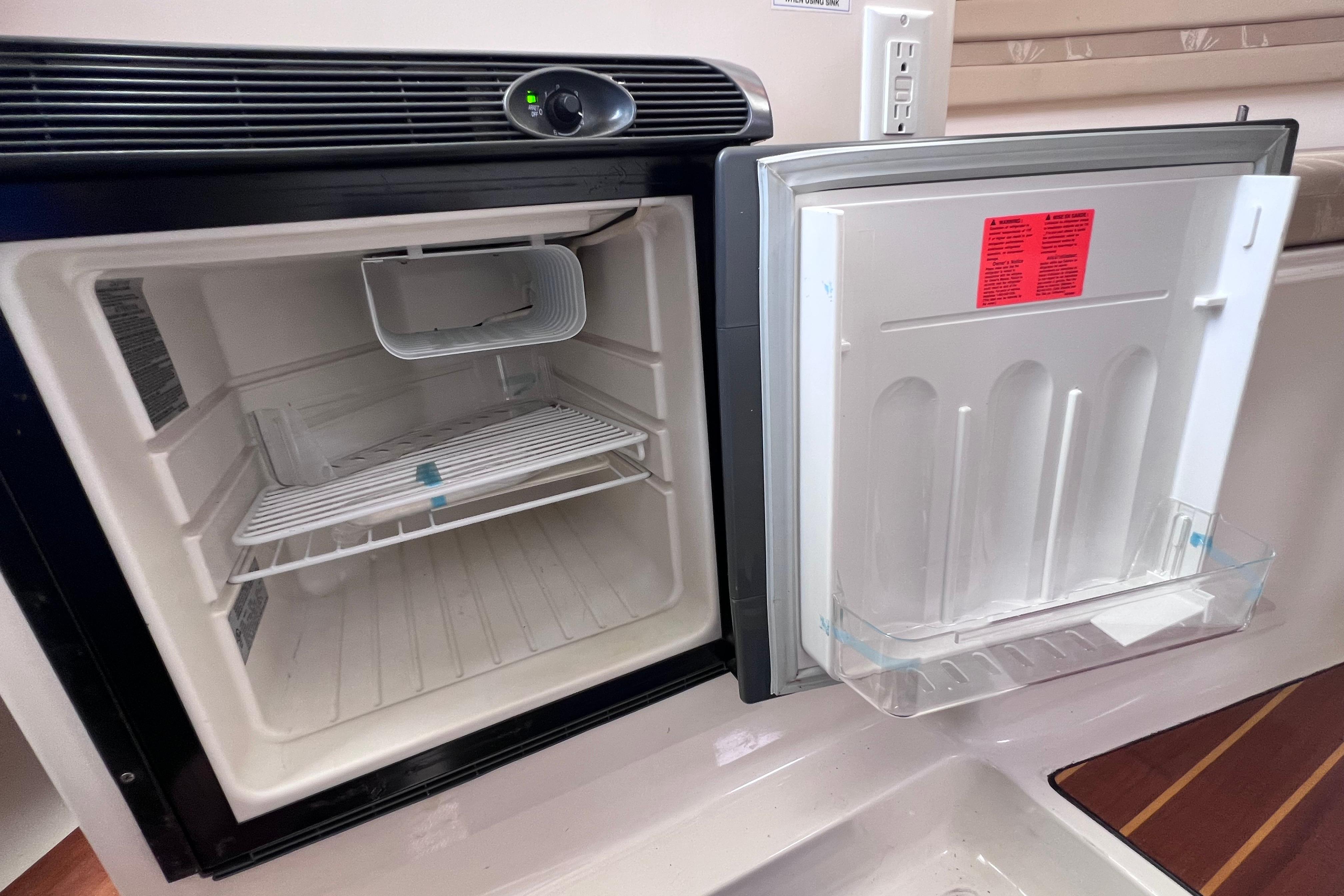 Open refrigerator inside a 2004 Pursuit 2870 Walkaround boat, showing empty shelves and door storage.