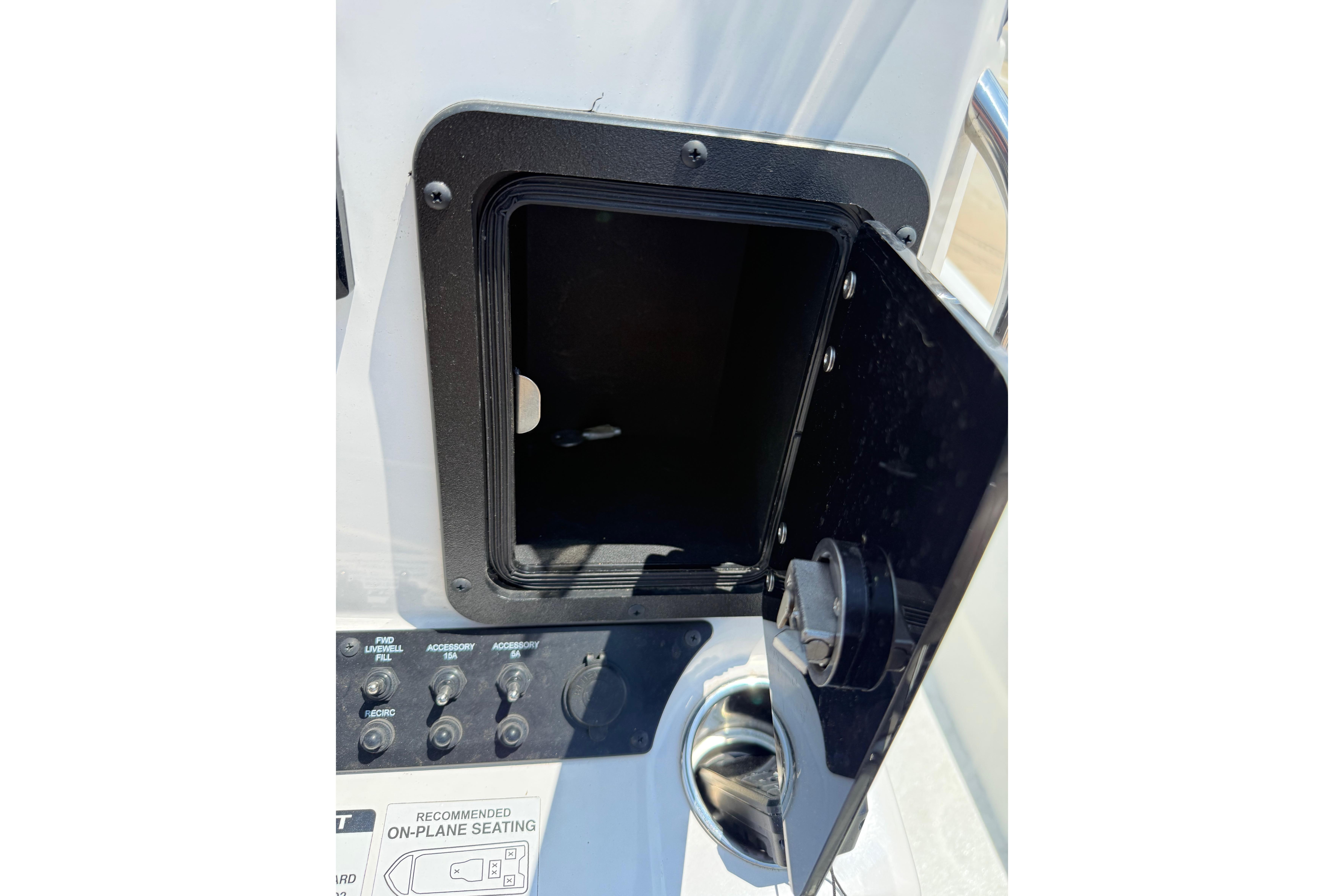 Open storage compartment on 2025 Avid 22 Recon boat, showcasing control panel and seating instructions.