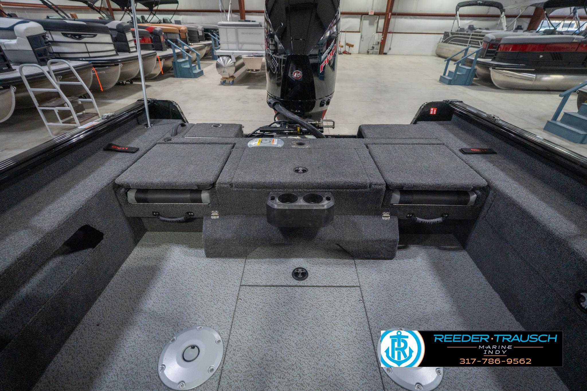 2026 Lund 2075 Impact XS boat interior with storage compartments and motor in showroom.