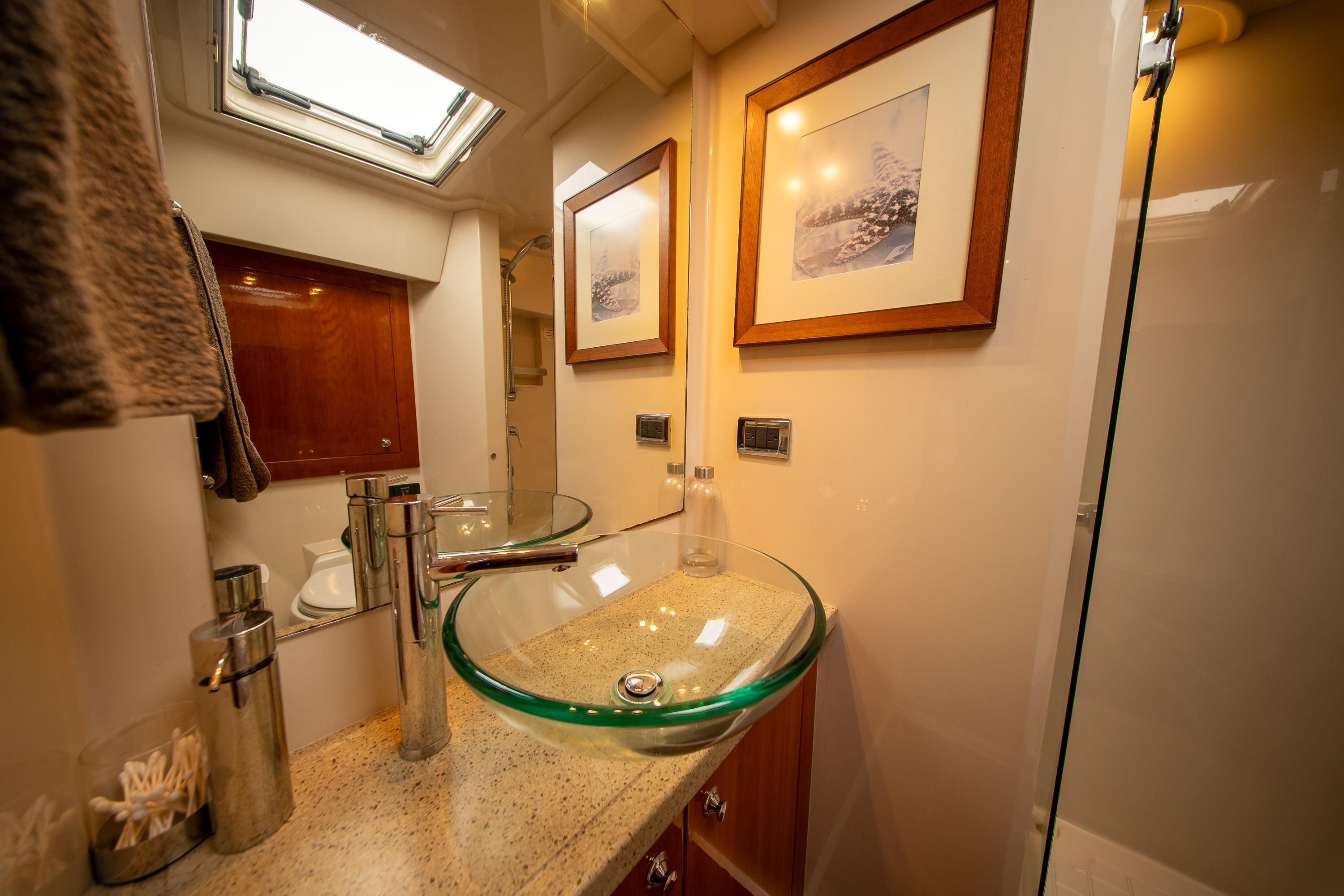 Luxurious bathroom in 2011 Riviera 5000 Sport Yacht with glass sink and elegant decor.