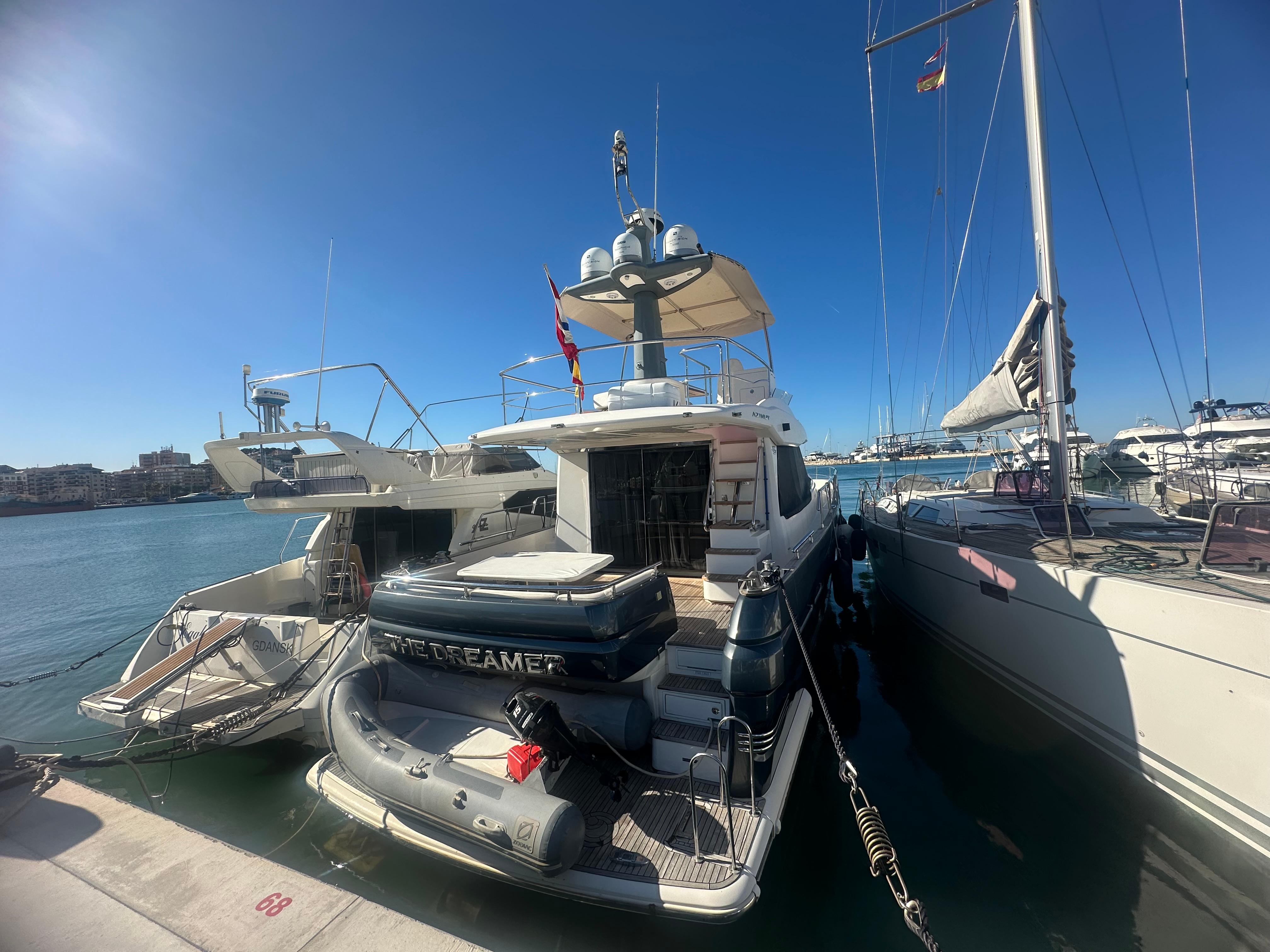 Azimut Magellano 50 yacht, 2014 model, docked at a marina under clear blue skies.