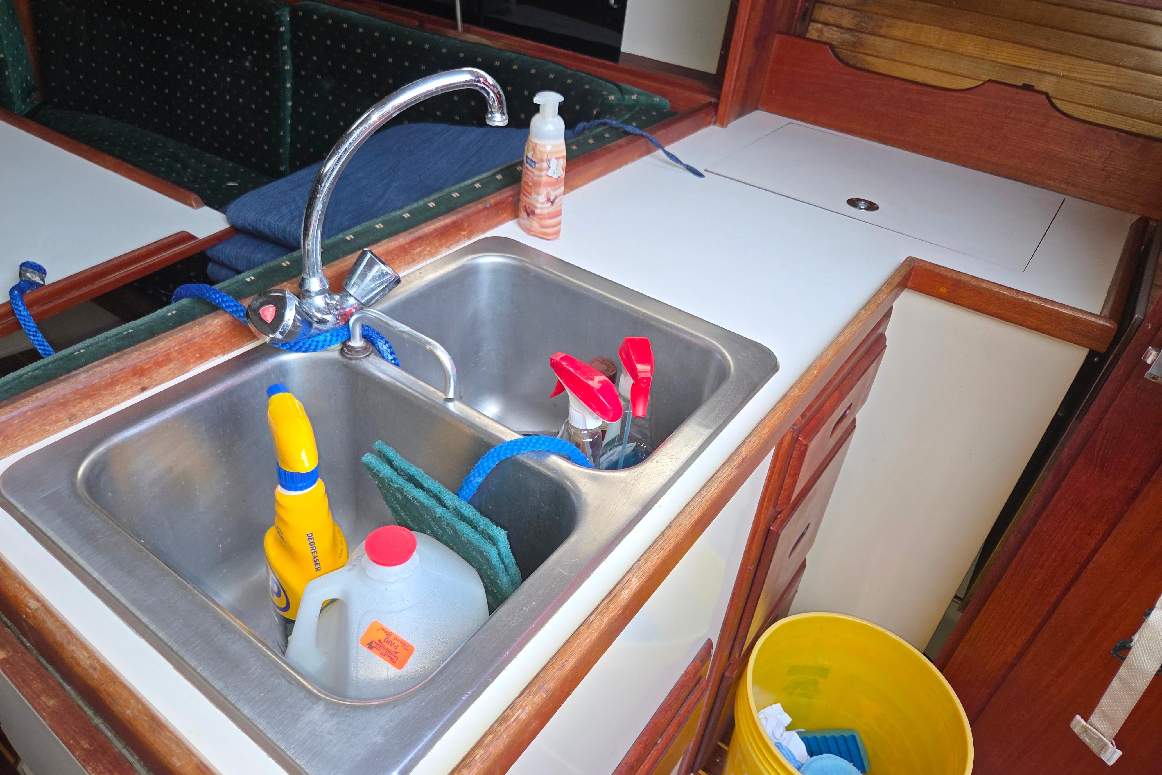 Galley sink in 1986 Catalina 355 yacht with cleaning supplies and faucet.