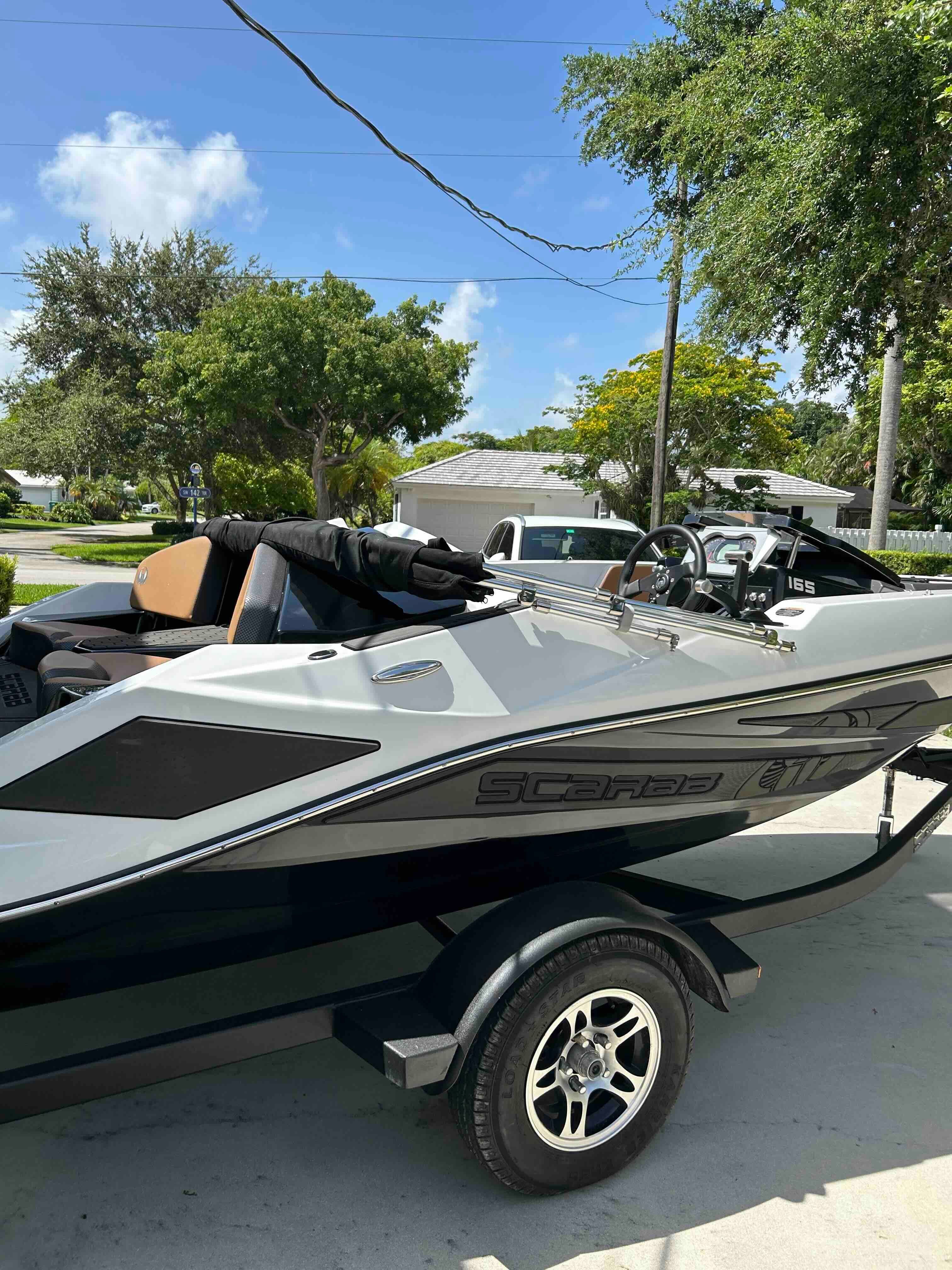 A 2022 Scarab 165 ID boat on a trailer in a sunny setting.