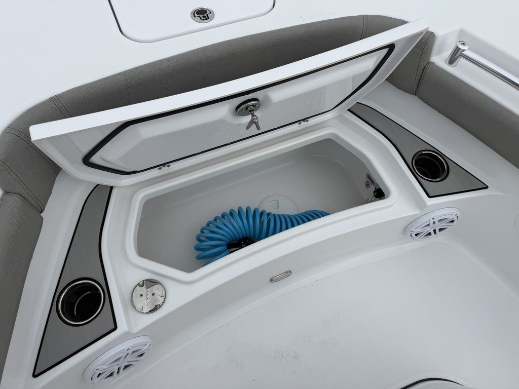 An open storage compartment on a Sportsman Masters 247OE Bay Boat with a blue hose.