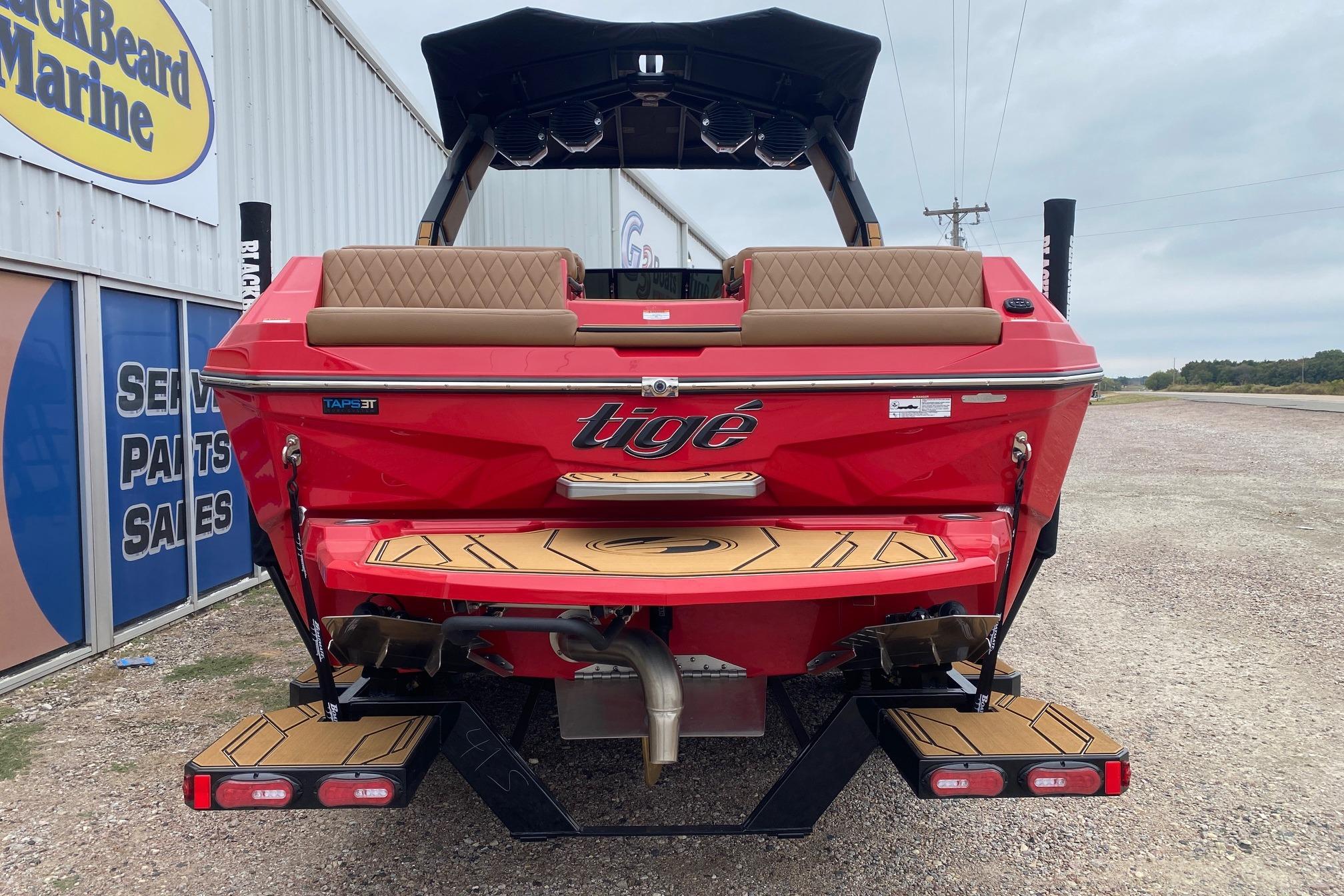 2026 Tigé Z3 boat in red, rear view at a marine dealership.